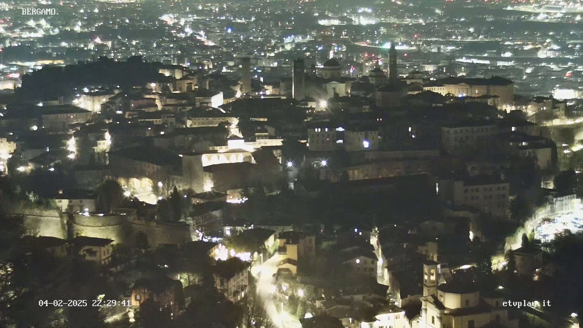 A nighttime aerial view of a city with illuminated buildings and streets.