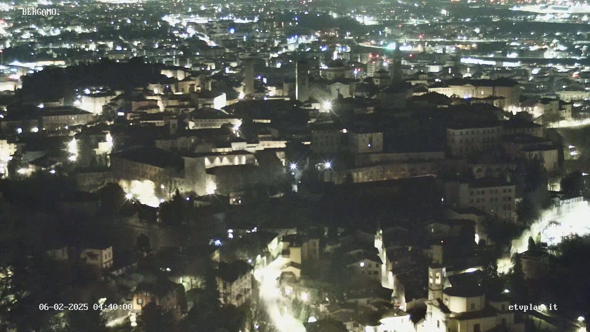 A nighttime, aerial view of a city with illuminated buildings and streets.