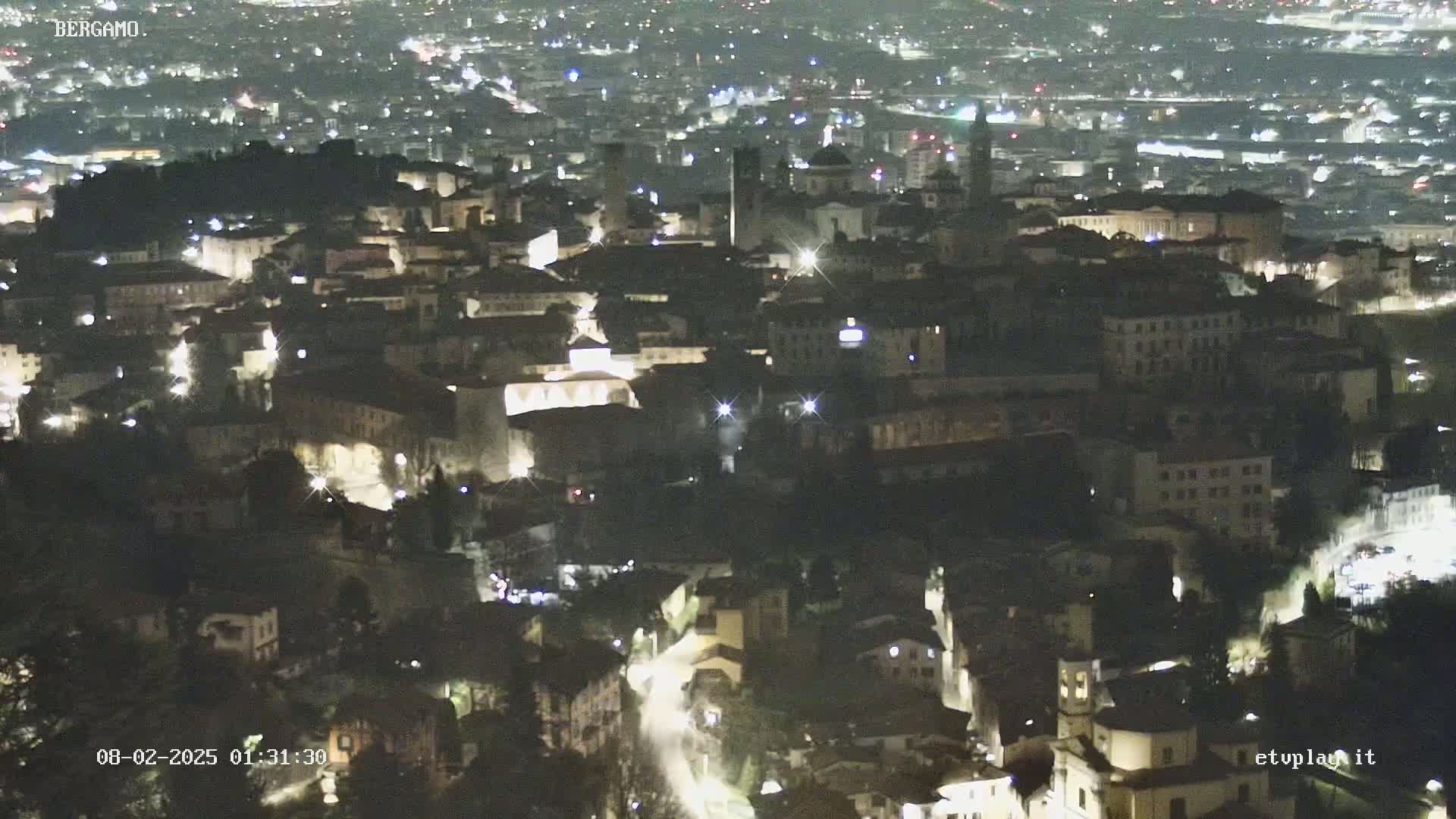 A nighttime, high-angle view of a city illuminated by streetlights.