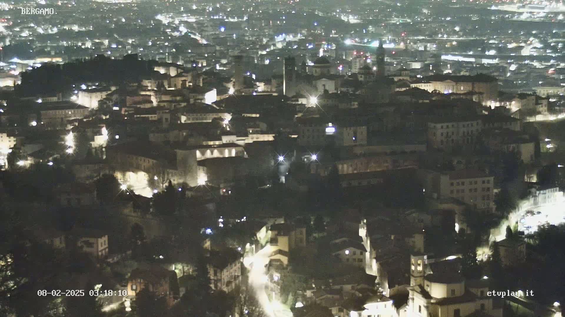 A nighttime, high-angle view of a city with many illuminated buildings and streets.