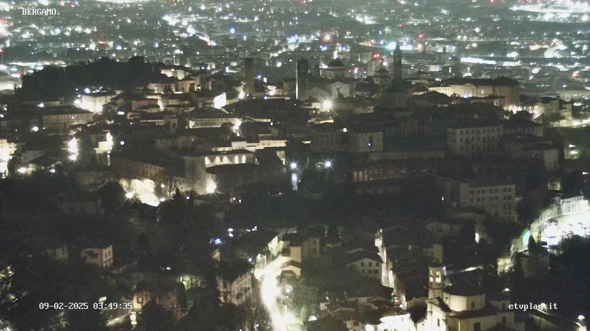 A nighttime, aerial view shows a city illuminated by streetlights and building lights.
