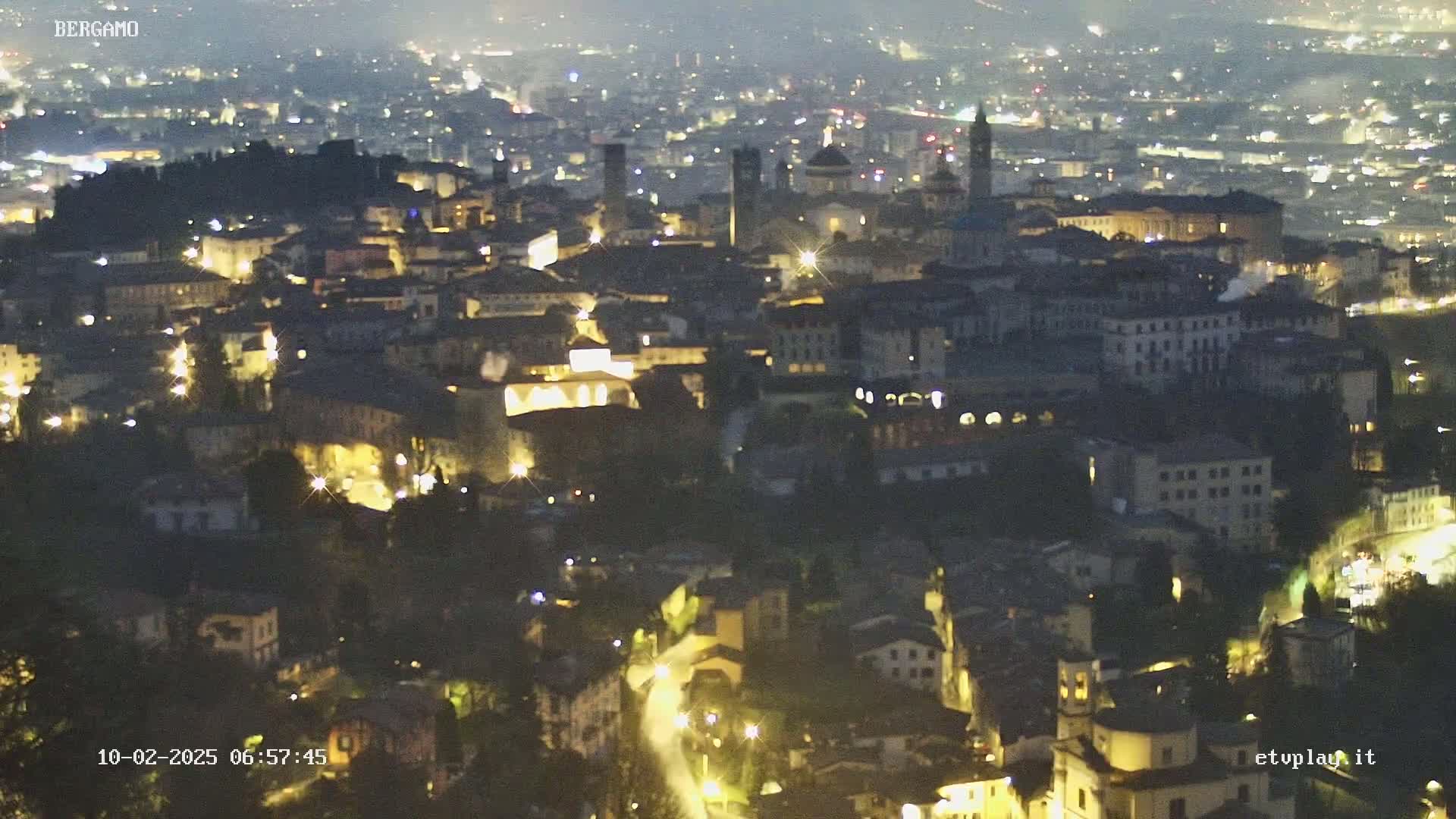 A nighttime, high-angle view of a city illuminated by streetlights.