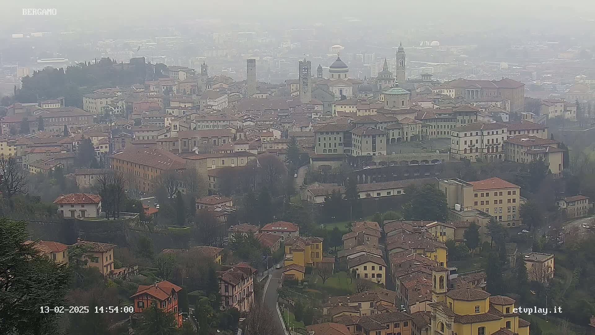 A hazy, overcast view of a sprawling city with numerous buildings of varying sizes and architectural styles.
