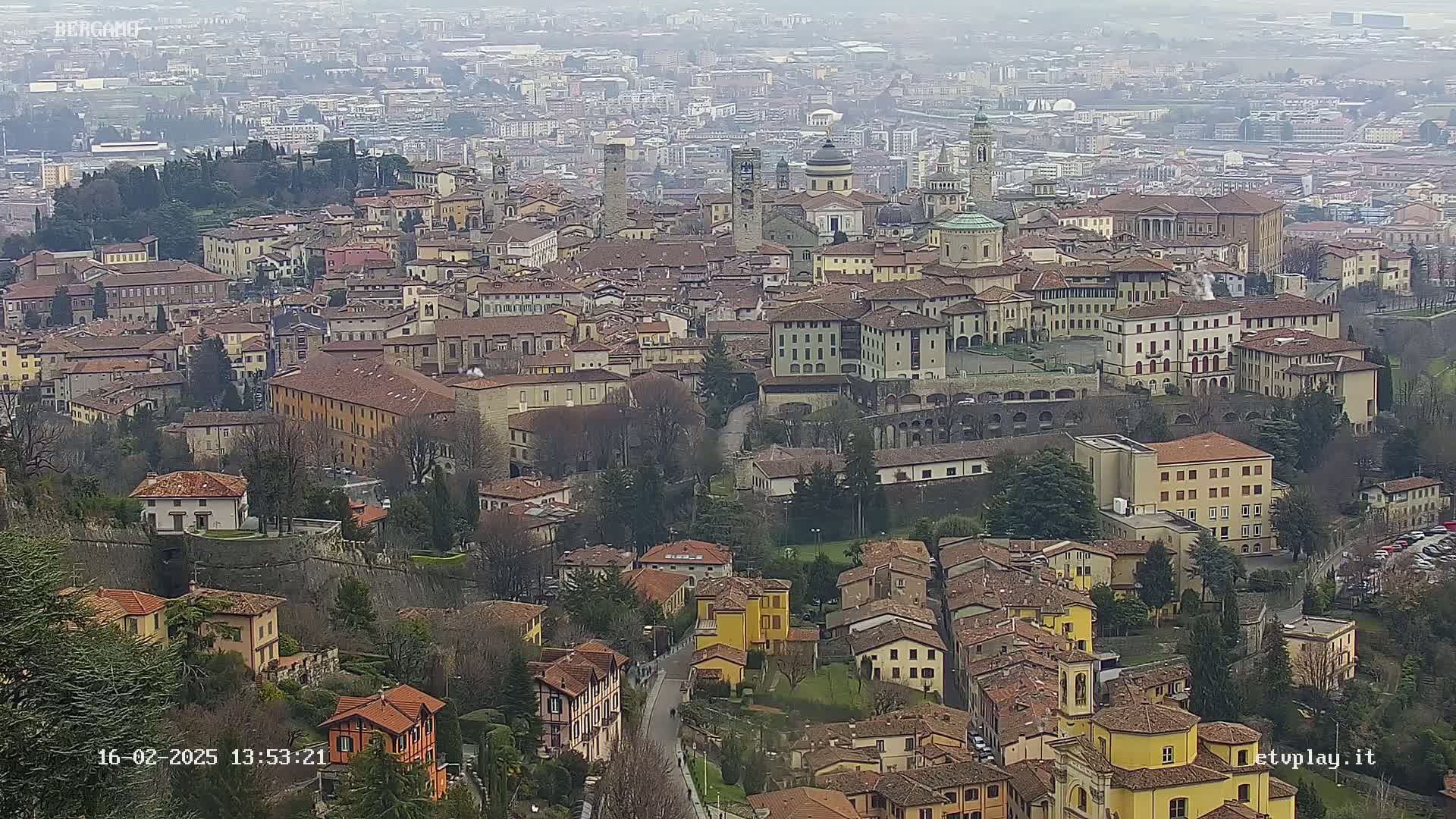 An expansive view of a city with numerous closely packed buildings of varying heights and styles, under an overcast sky.