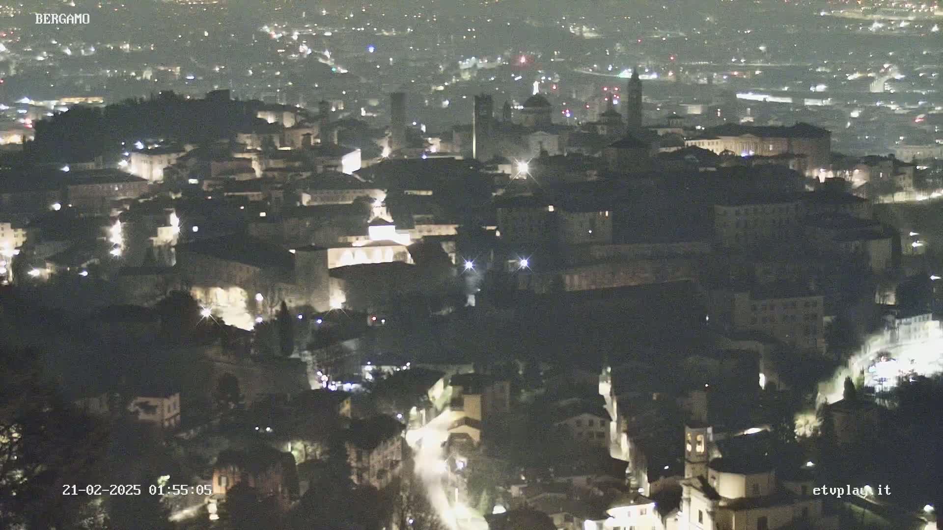 A nighttime aerial view of a city, with many buildings illuminated by lights.
