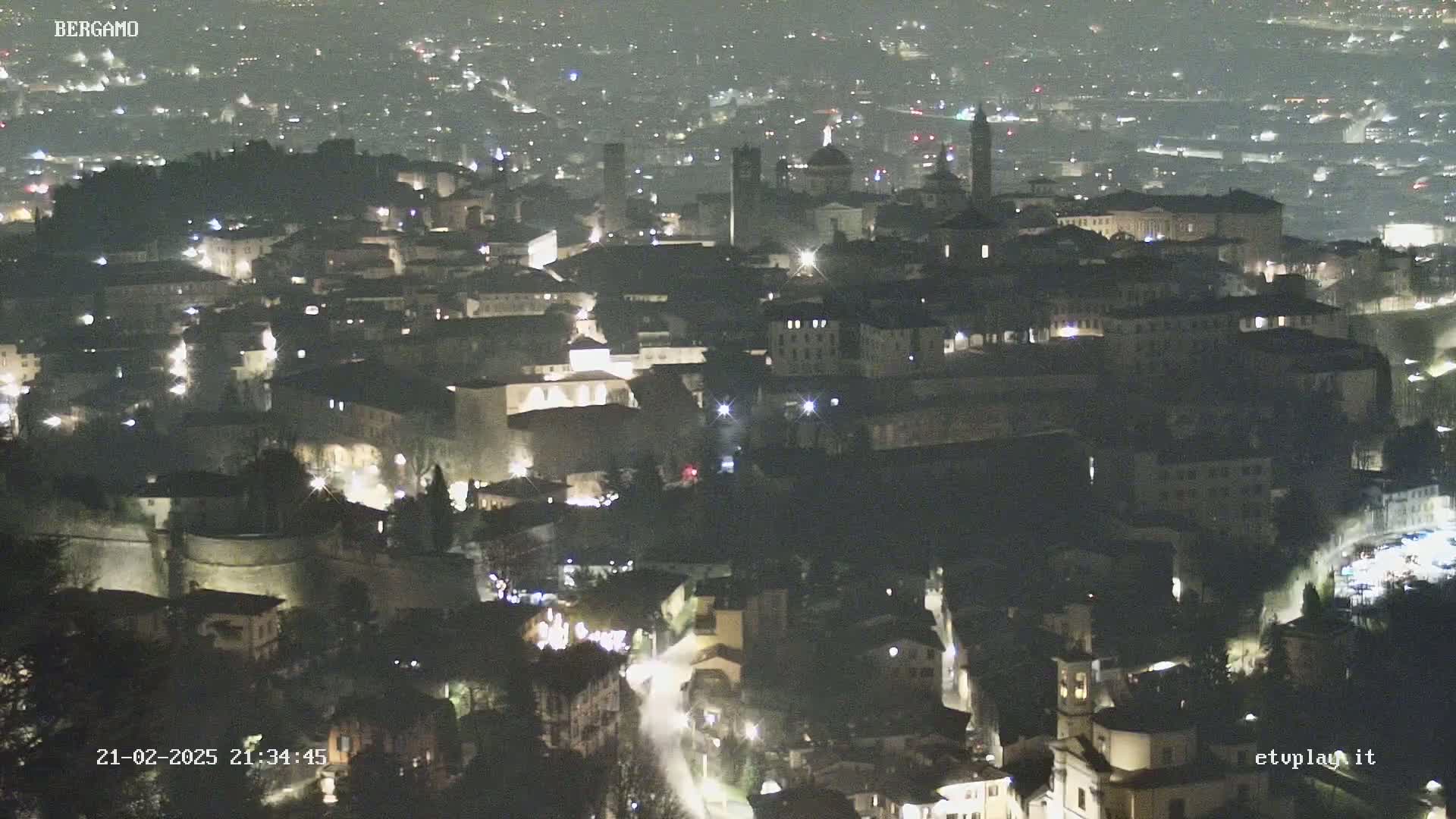 A nighttime, high-angle view shows a city with illuminated buildings and streets.