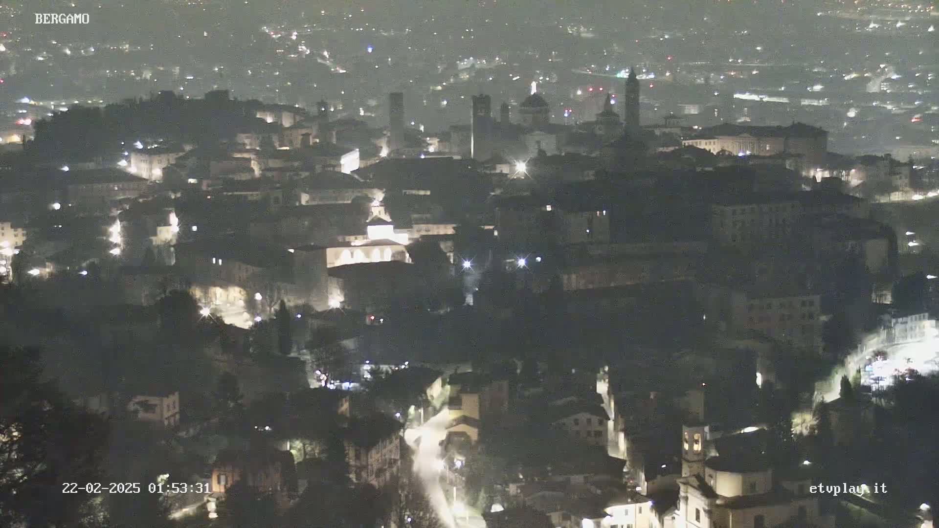 A nighttime aerial view of a city with dimly lit buildings and streets.