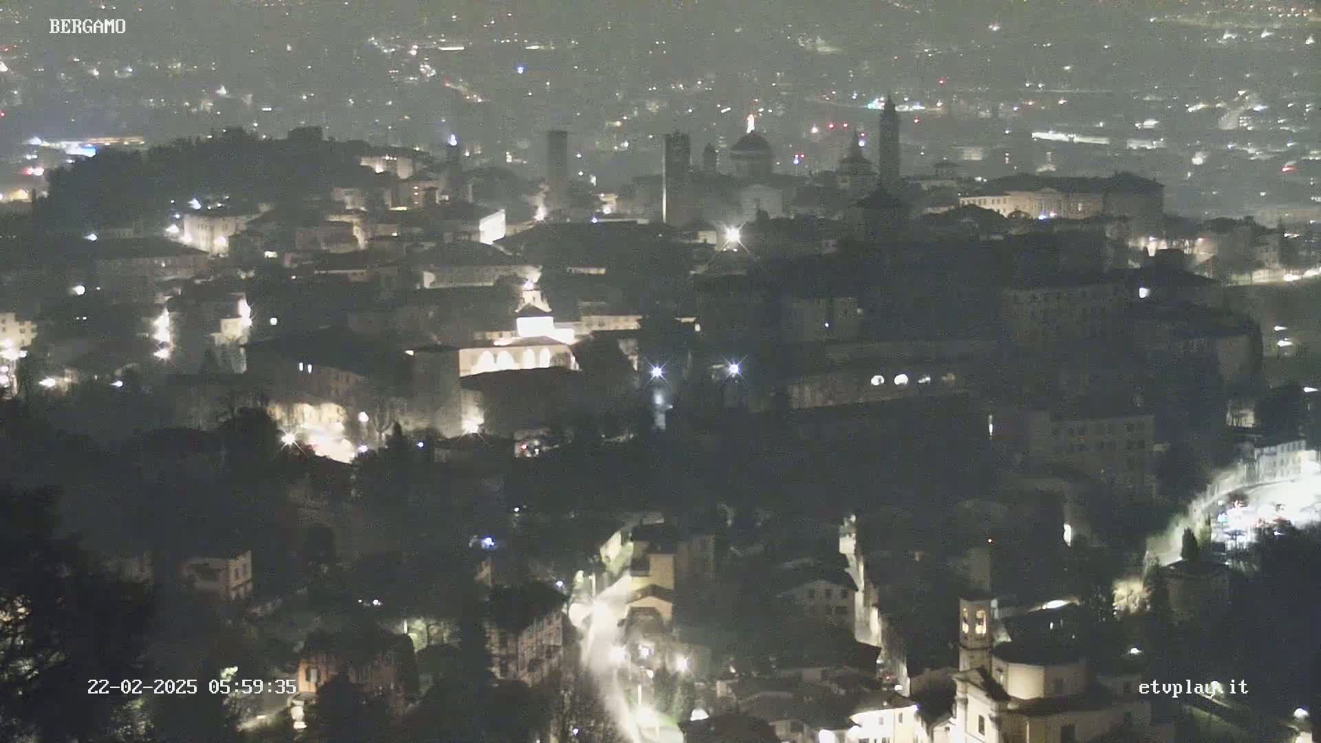 A nighttime aerial view of a city with dimly lit buildings and streets.