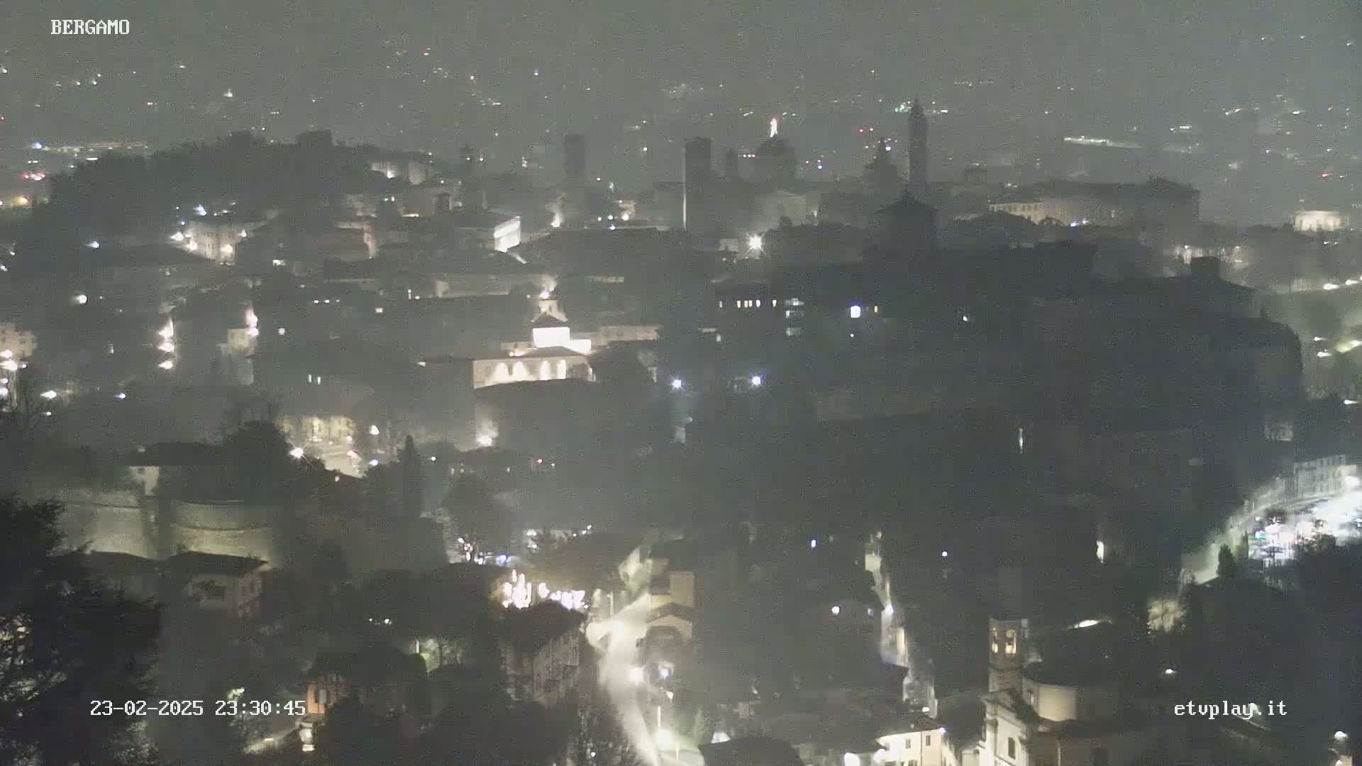 A nighttime, hazy view of a city with dimly lit buildings and streets.
