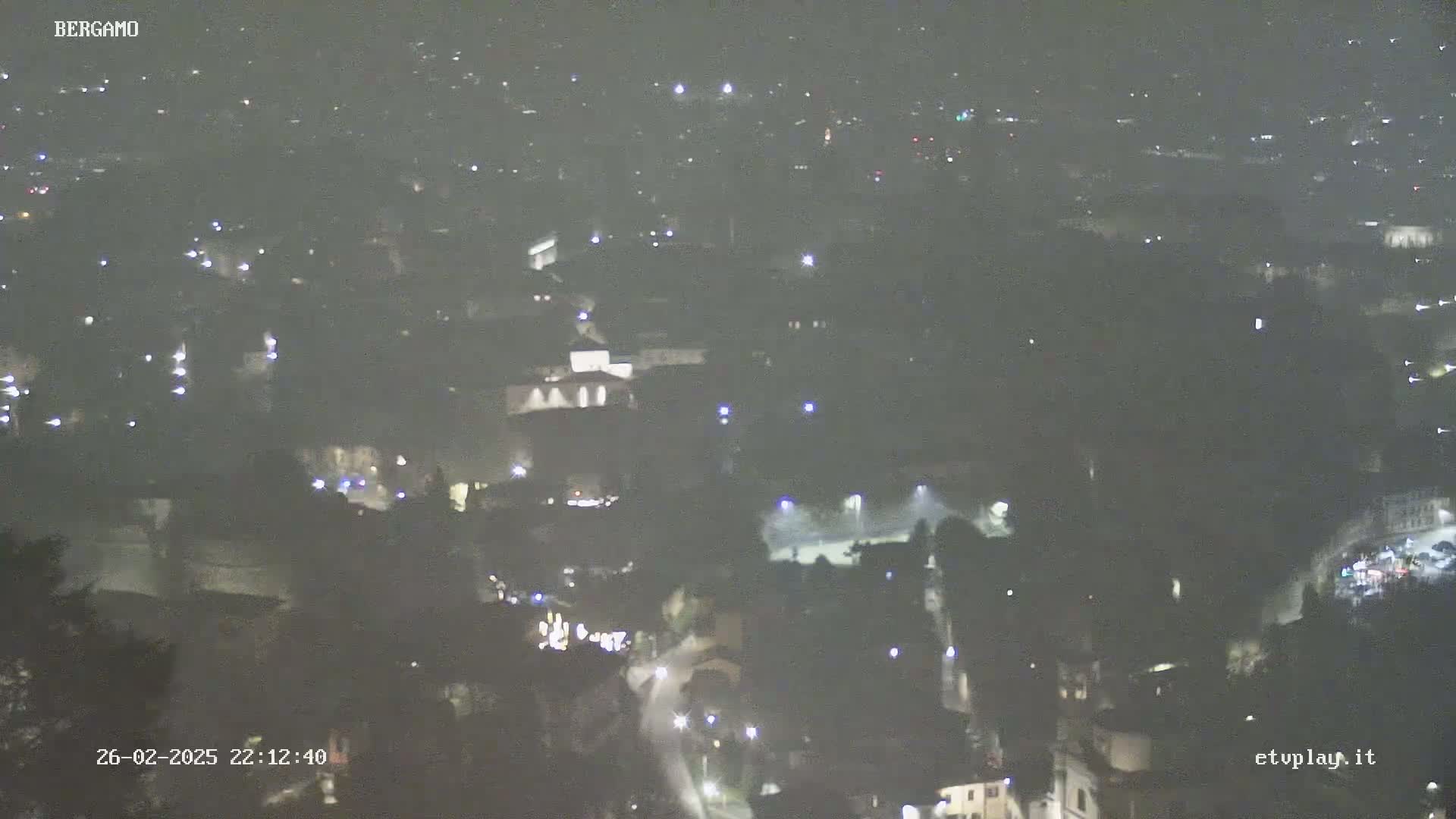 A hazy, nighttime, aerial view of a city with scattered lights.