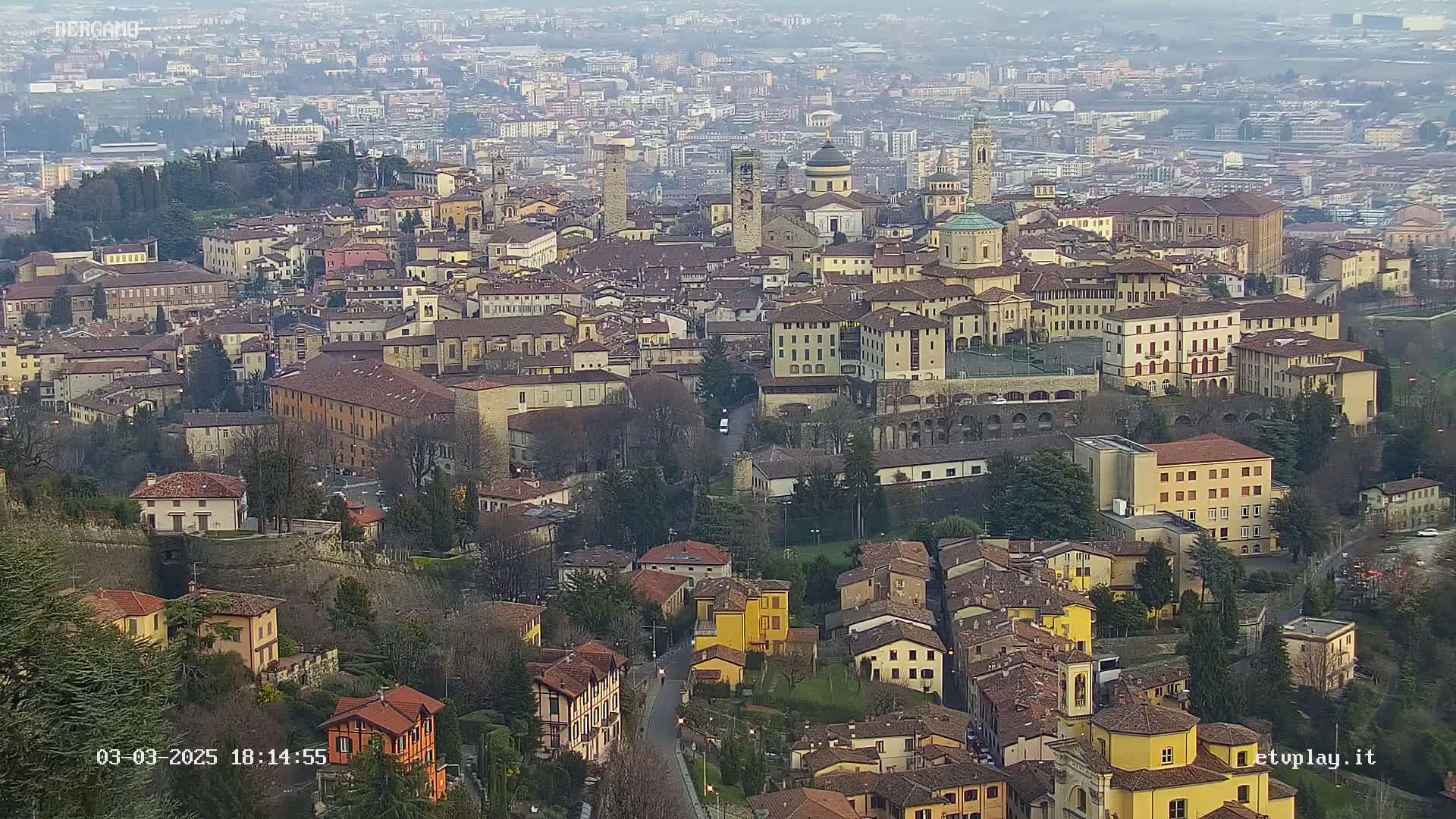 A sprawling city of tan and brown buildings nestled in a valley on an overcast day.