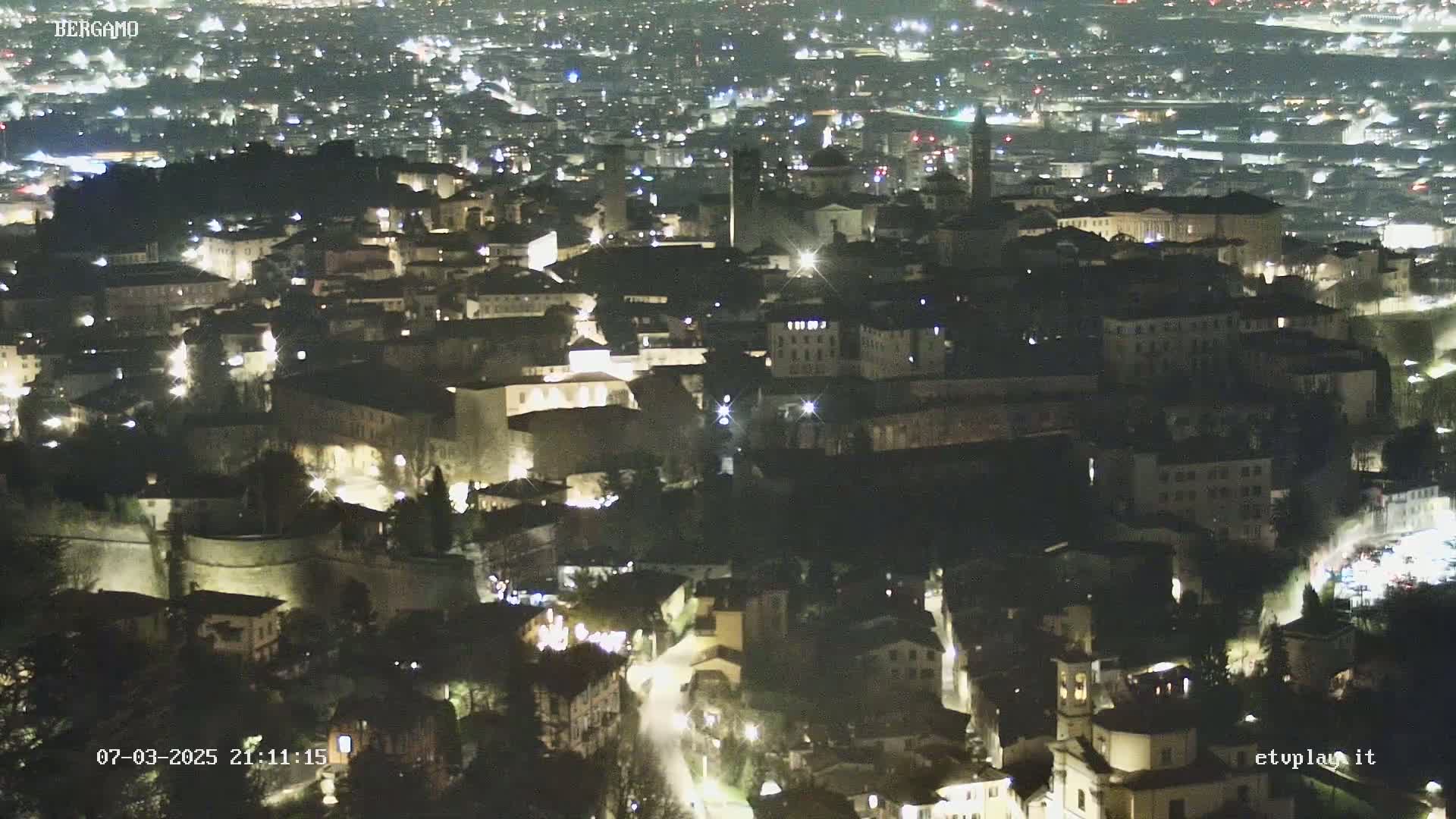 A nighttime aerial view of a city with illuminated buildings and streets.