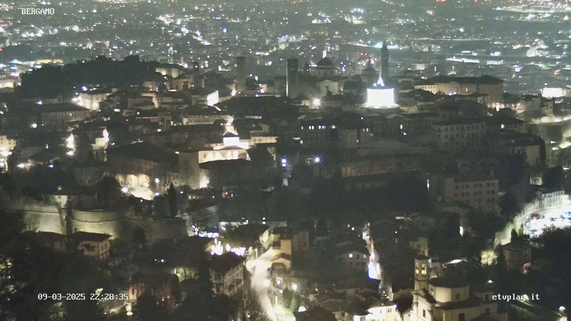A nighttime aerial view of a city with illuminated buildings and streets.