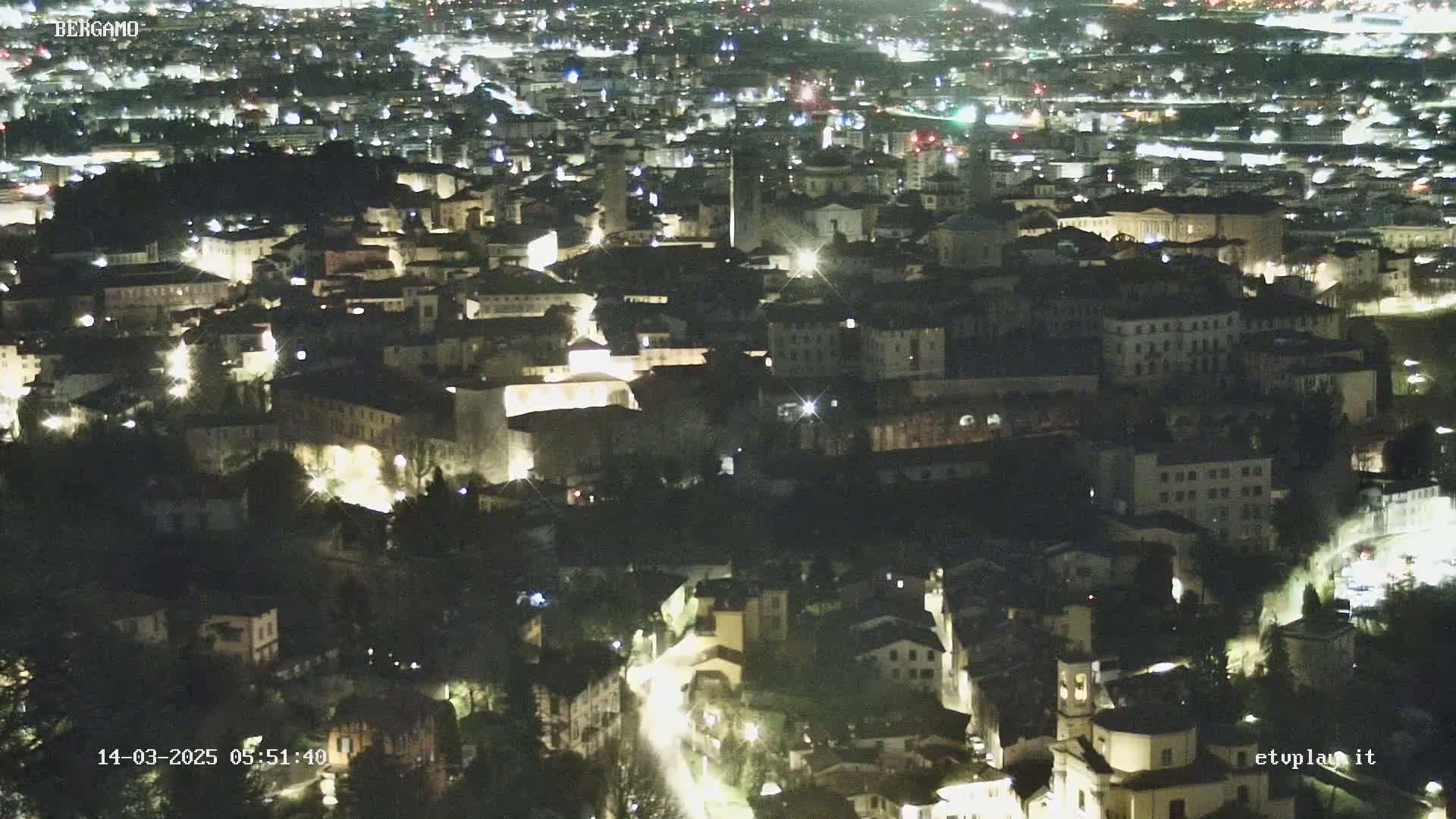 A nighttime aerial view of a city with many illuminated buildings and streets.