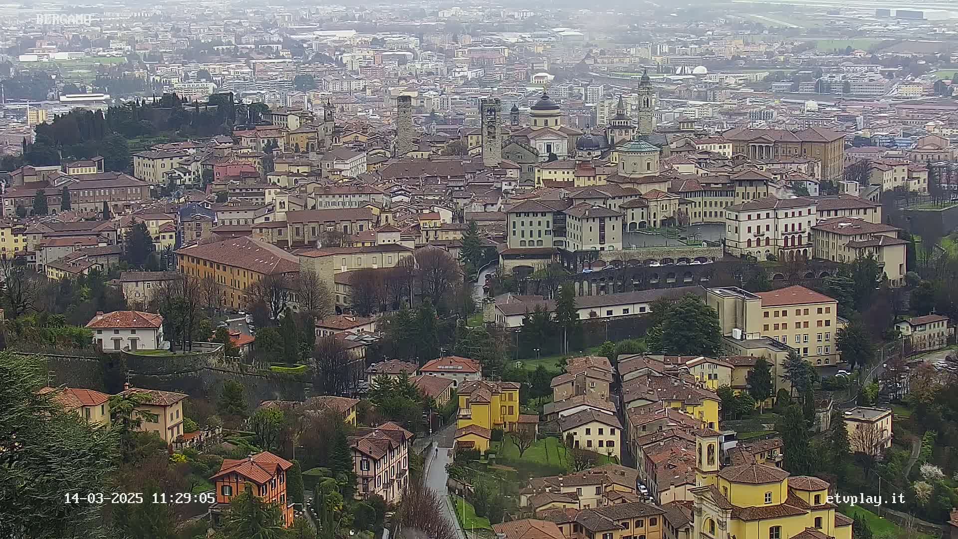 An aerial view of a densely packed city with many low-rise buildings, under an overcast sky.