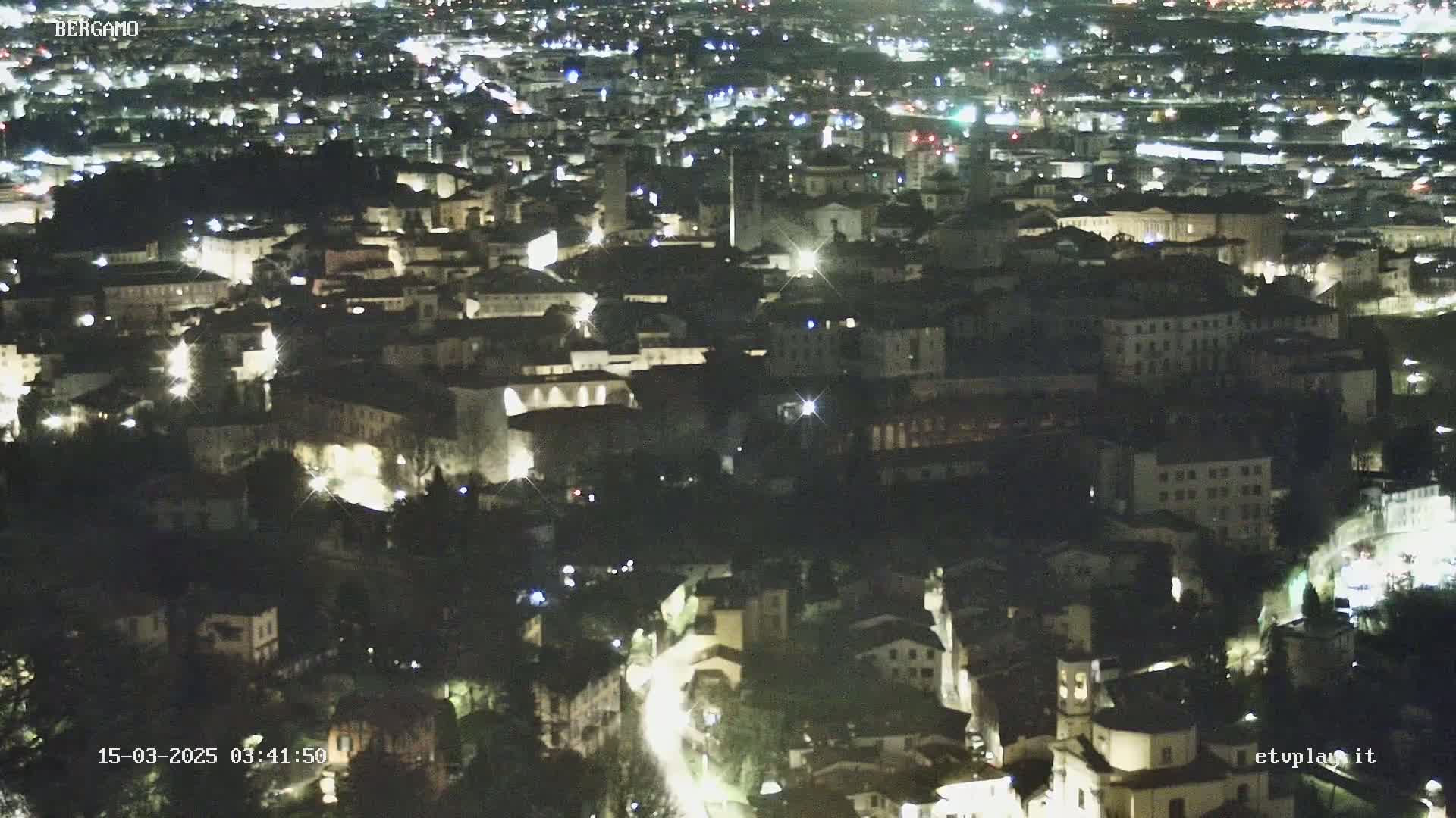 A nighttime, high-angle view of a city with illuminated buildings and streets.