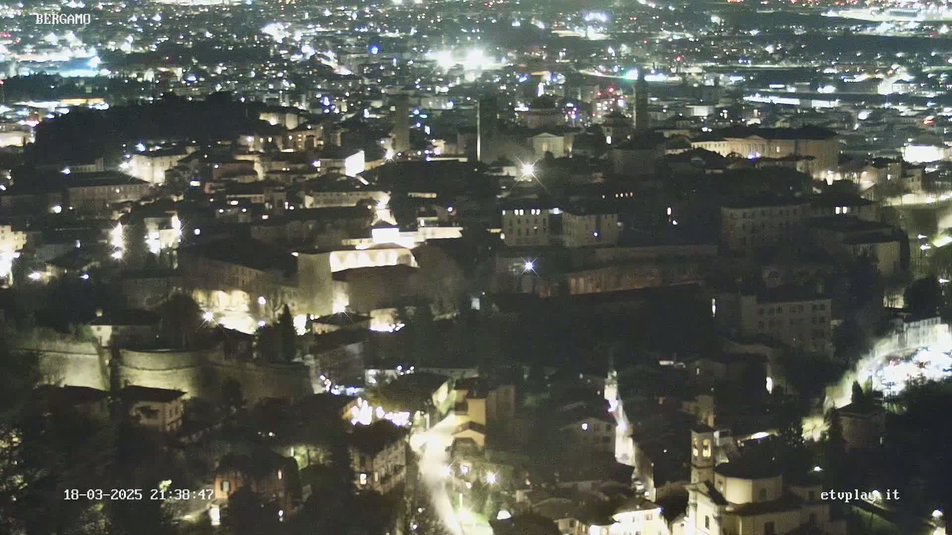 A nighttime aerial view of a city with illuminated buildings and streets.