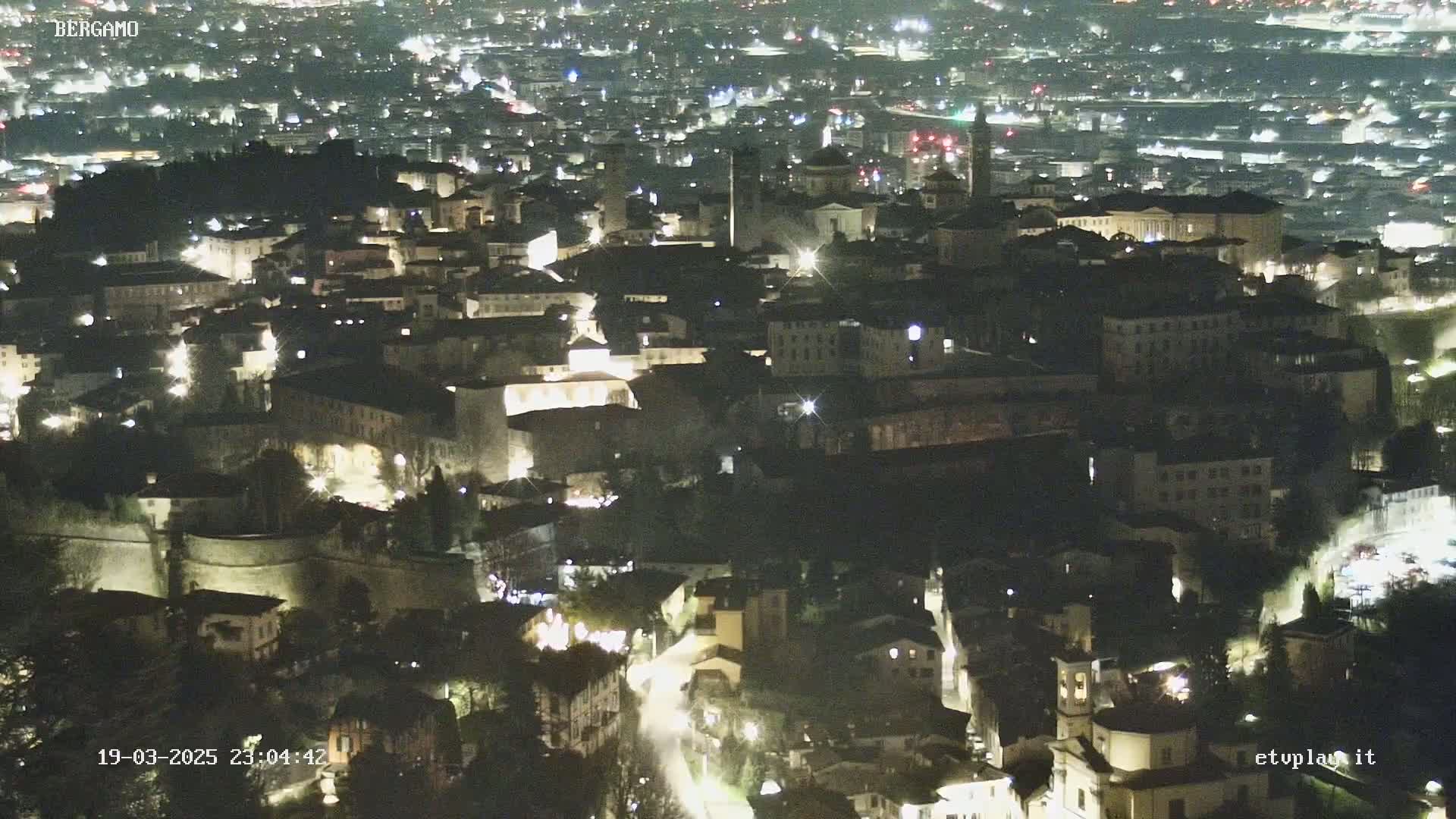 A nighttime, aerial view of a city with illuminated buildings and streets.