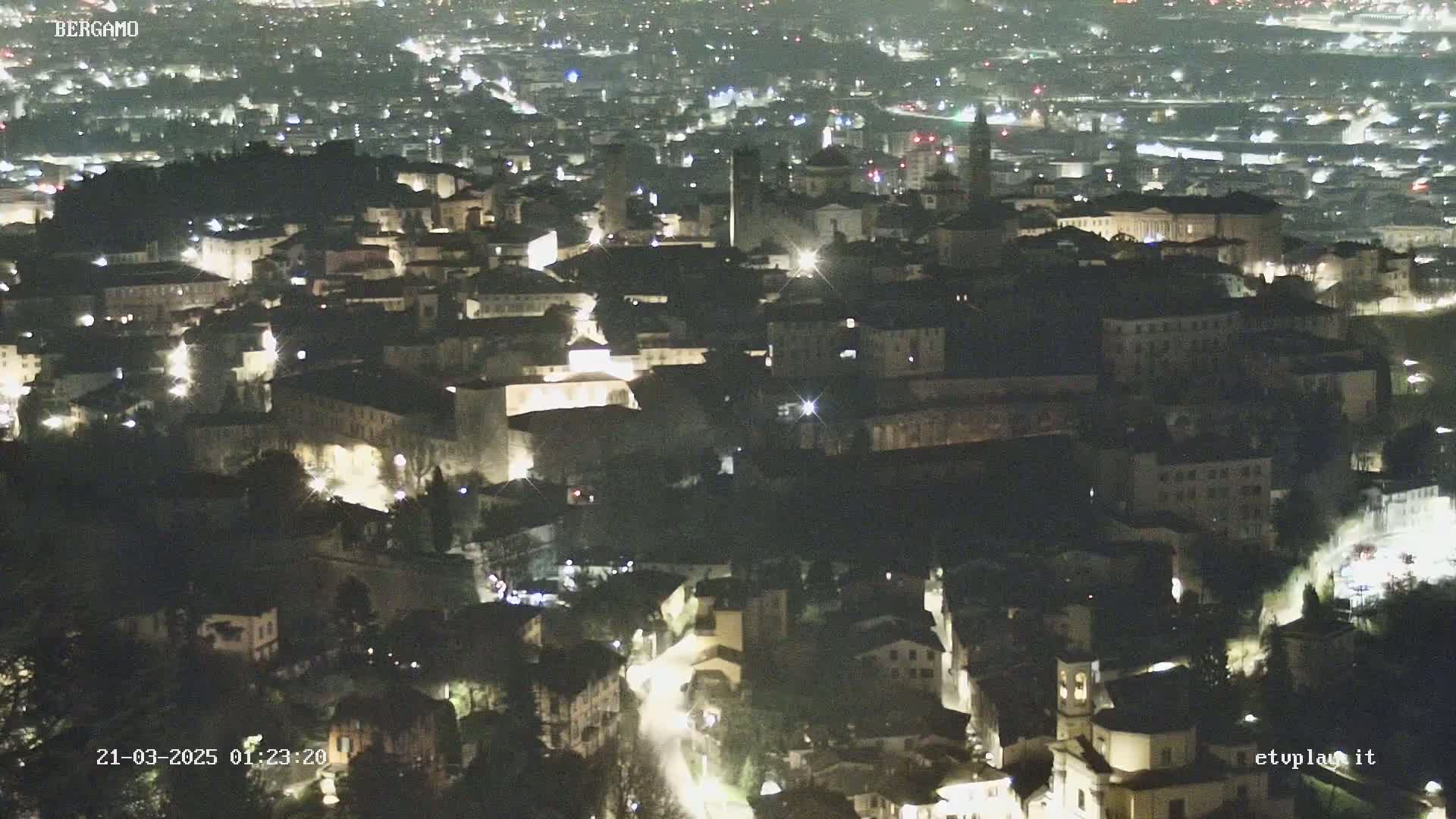 A nighttime, high-angle view of a city with many buildings lit up.