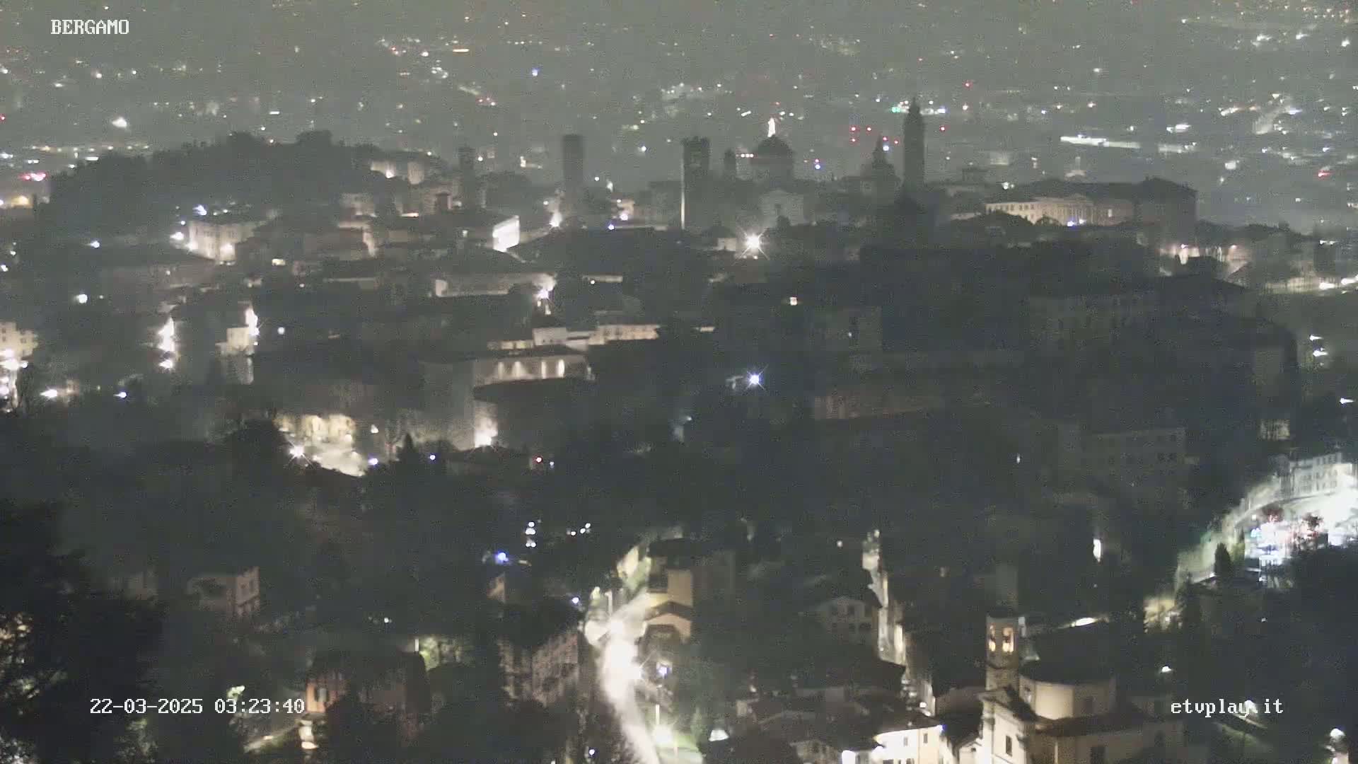 A nighttime, hazy view of a city with dimly lit buildings and streets, showing some prominent structures.