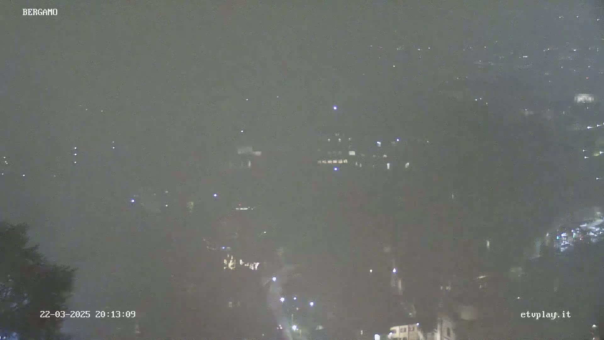 A hazy, nighttime view of a city with sparsely visible lights.