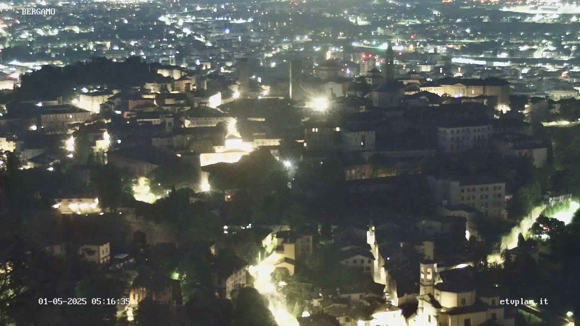 A nighttime aerial view of a city with many illuminated buildings and streets.