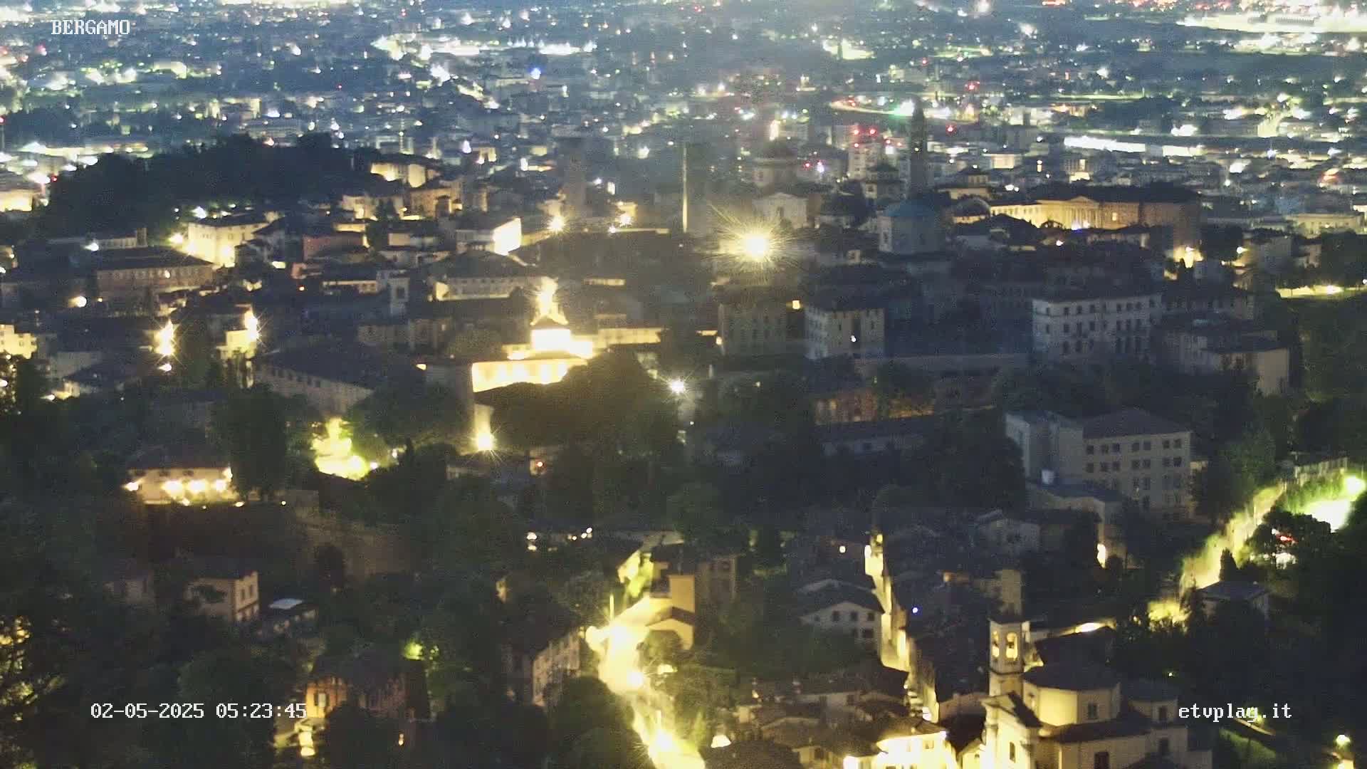 A nighttime aerial view of a city with illuminated buildings and streets.