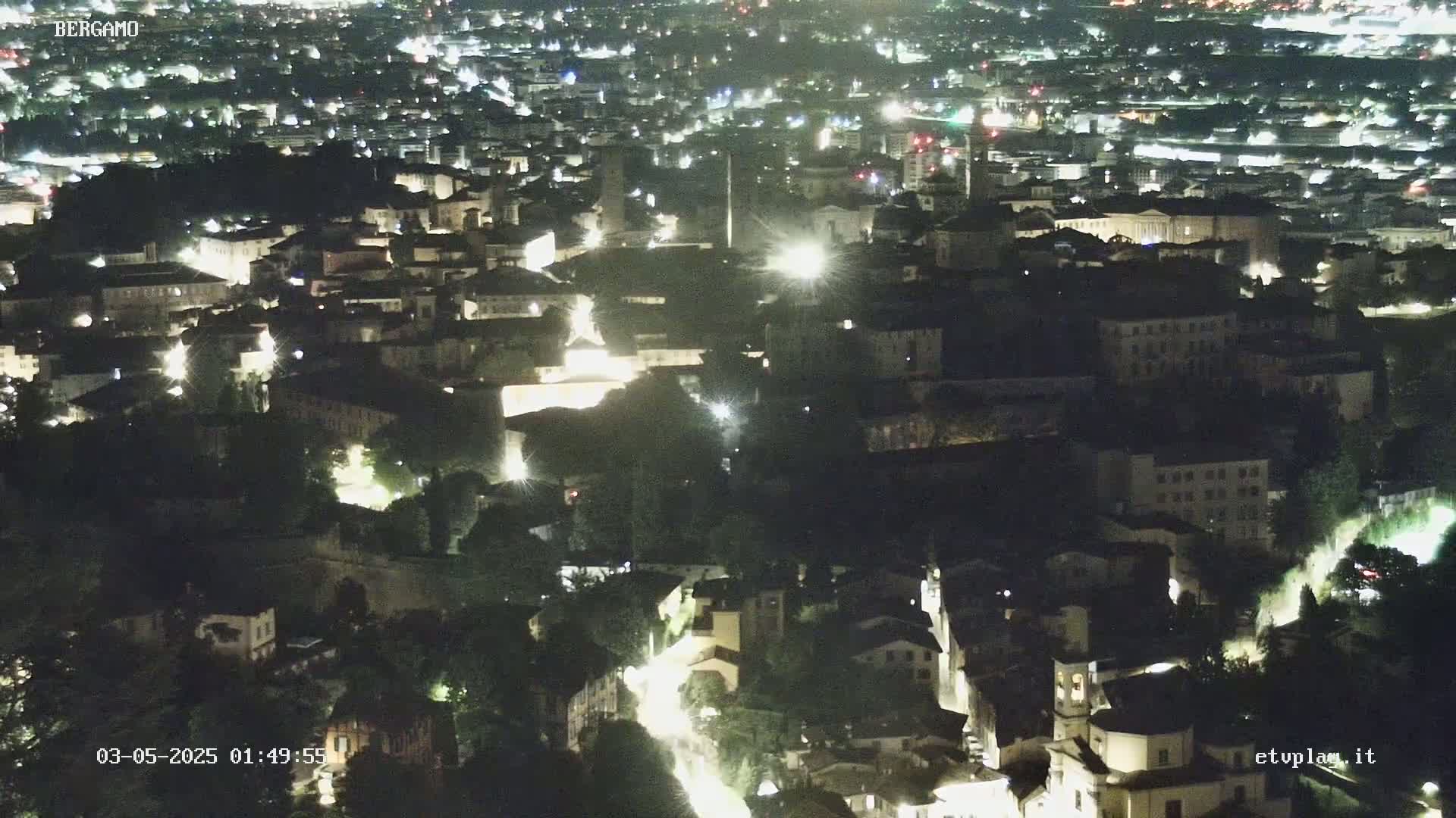 A nighttime aerial view of a city with many illuminated buildings and roads.