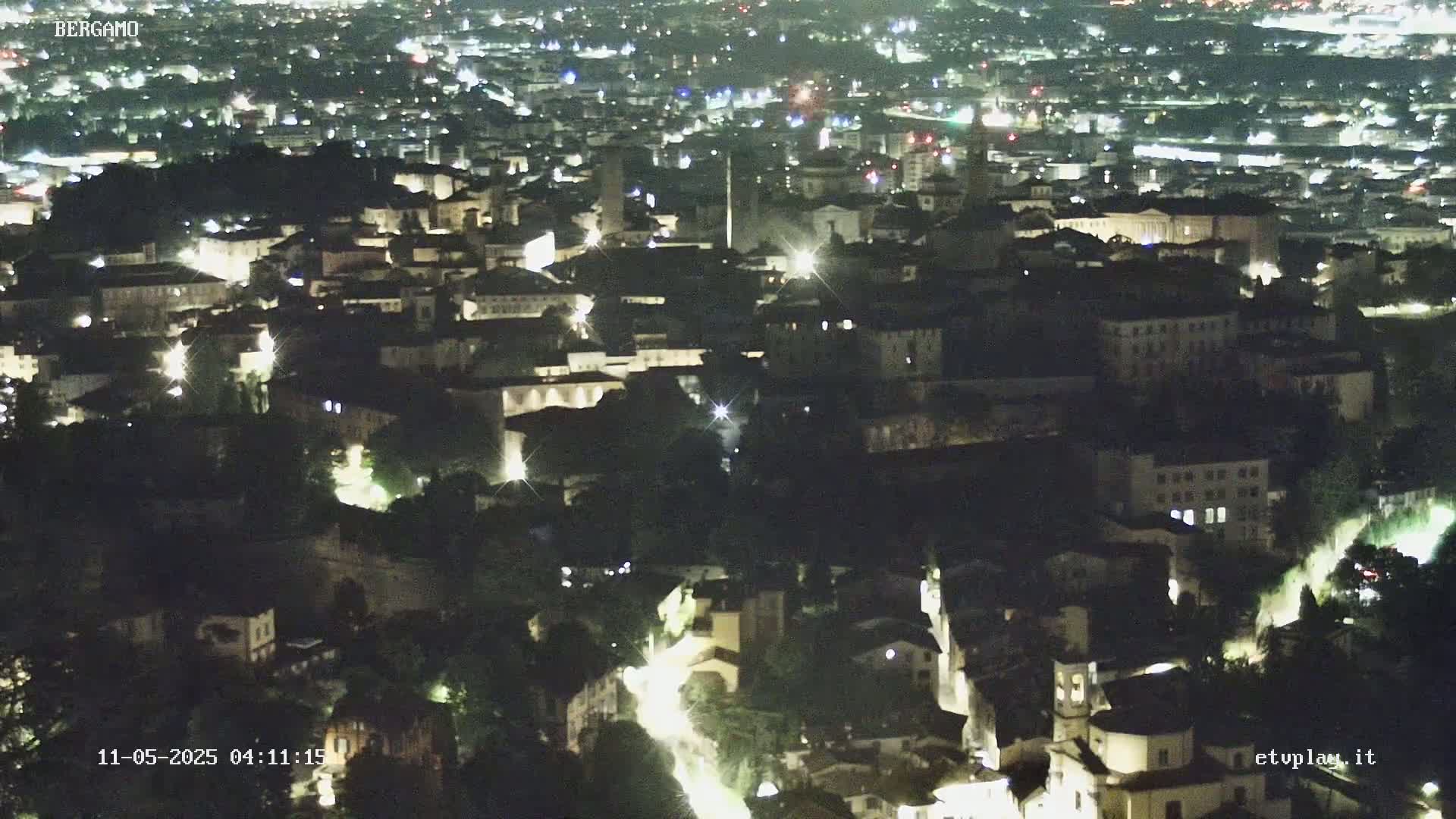 A nighttime aerial view of a city, showing numerous illuminated buildings and streets.