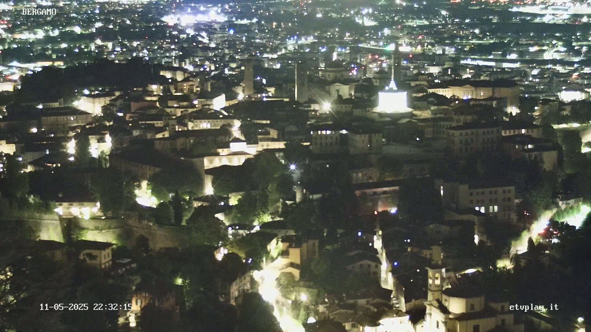 A nighttime aerial view shows a city with numerous illuminated buildings and streets.