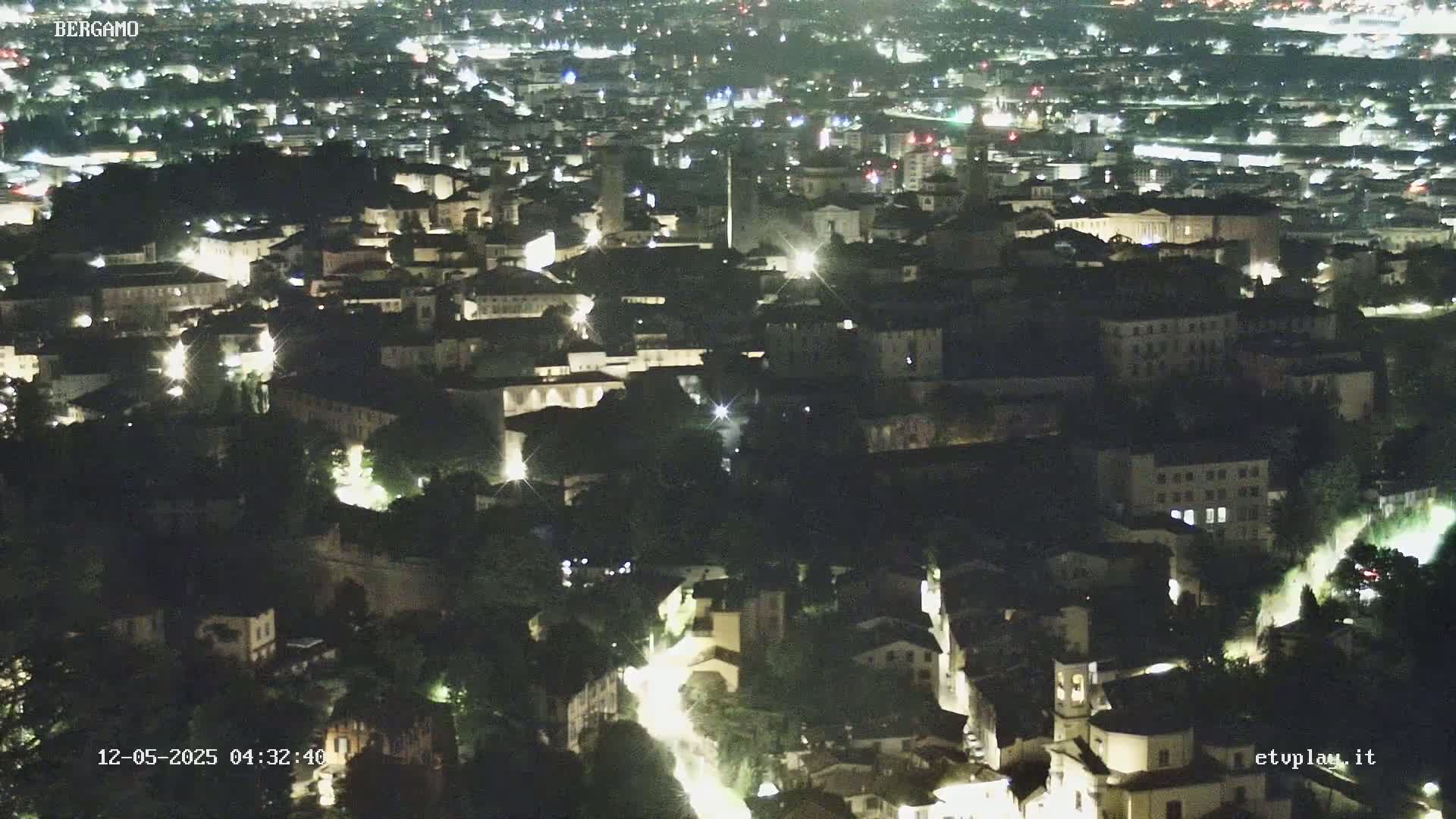 A nighttime aerial view shows a city with illuminated buildings and streets.