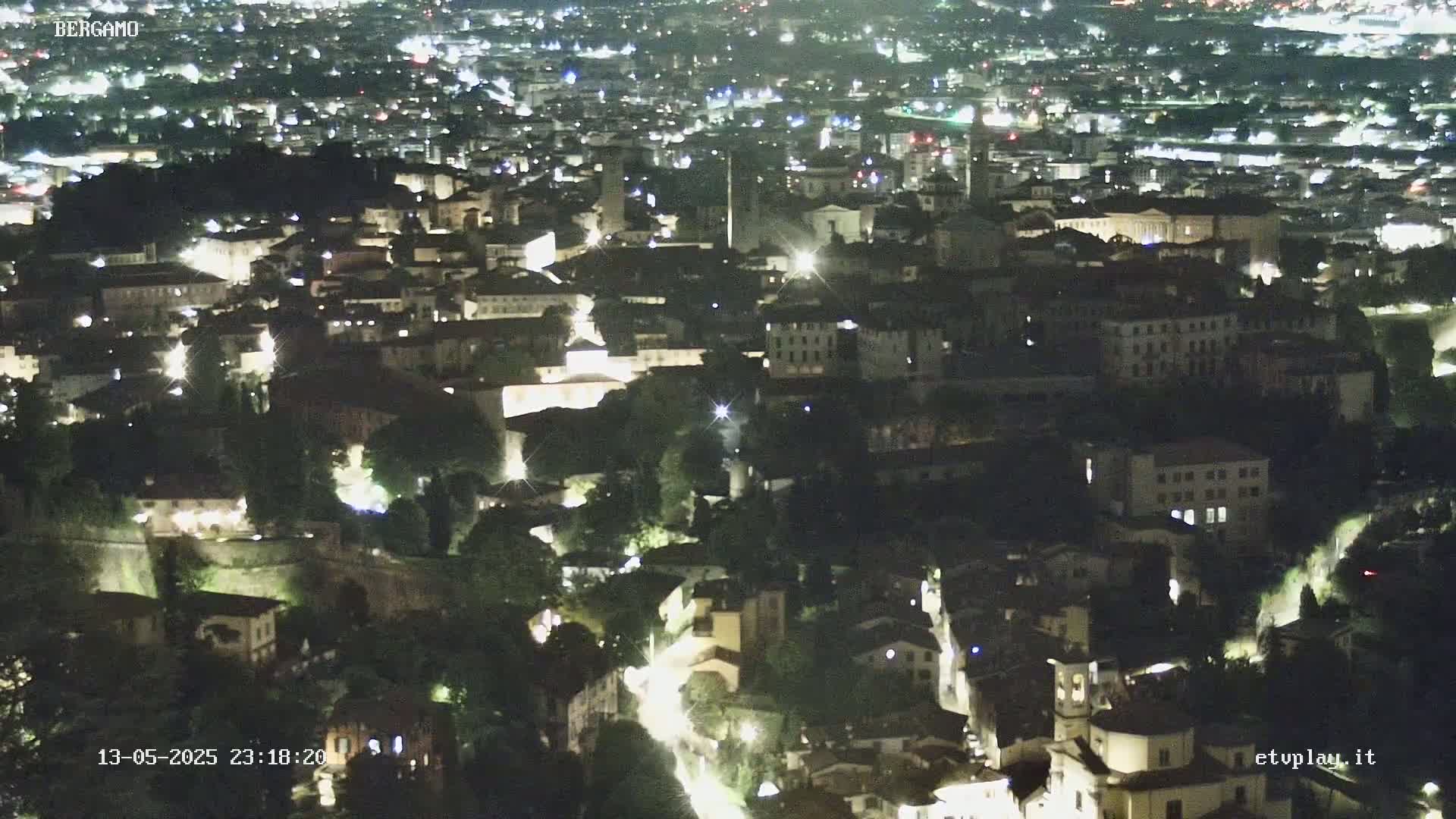 A nighttime, high-angle view of a densely populated city with illuminated buildings and streets.