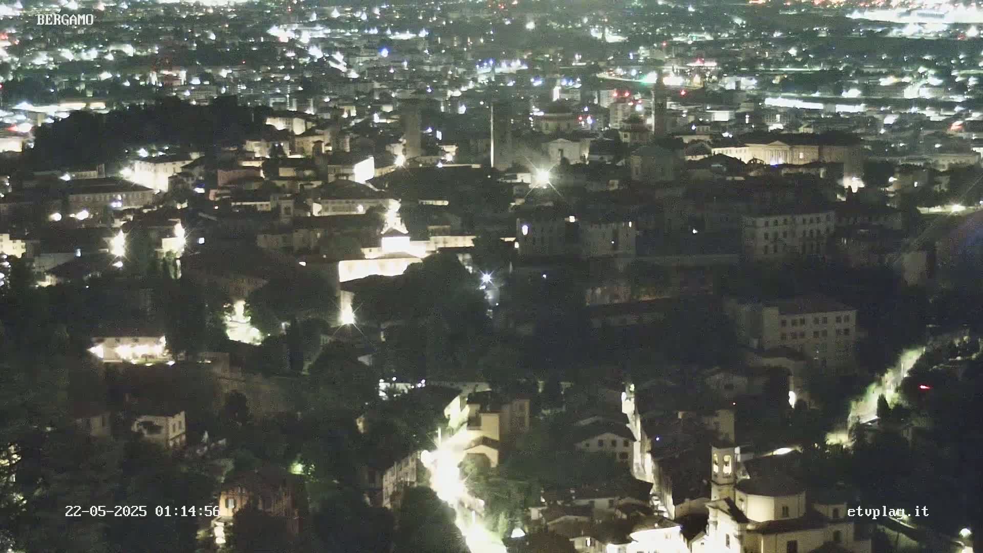 A nighttime, high-angle view of a city with numerous buildings illuminated by streetlights and other sources of light.