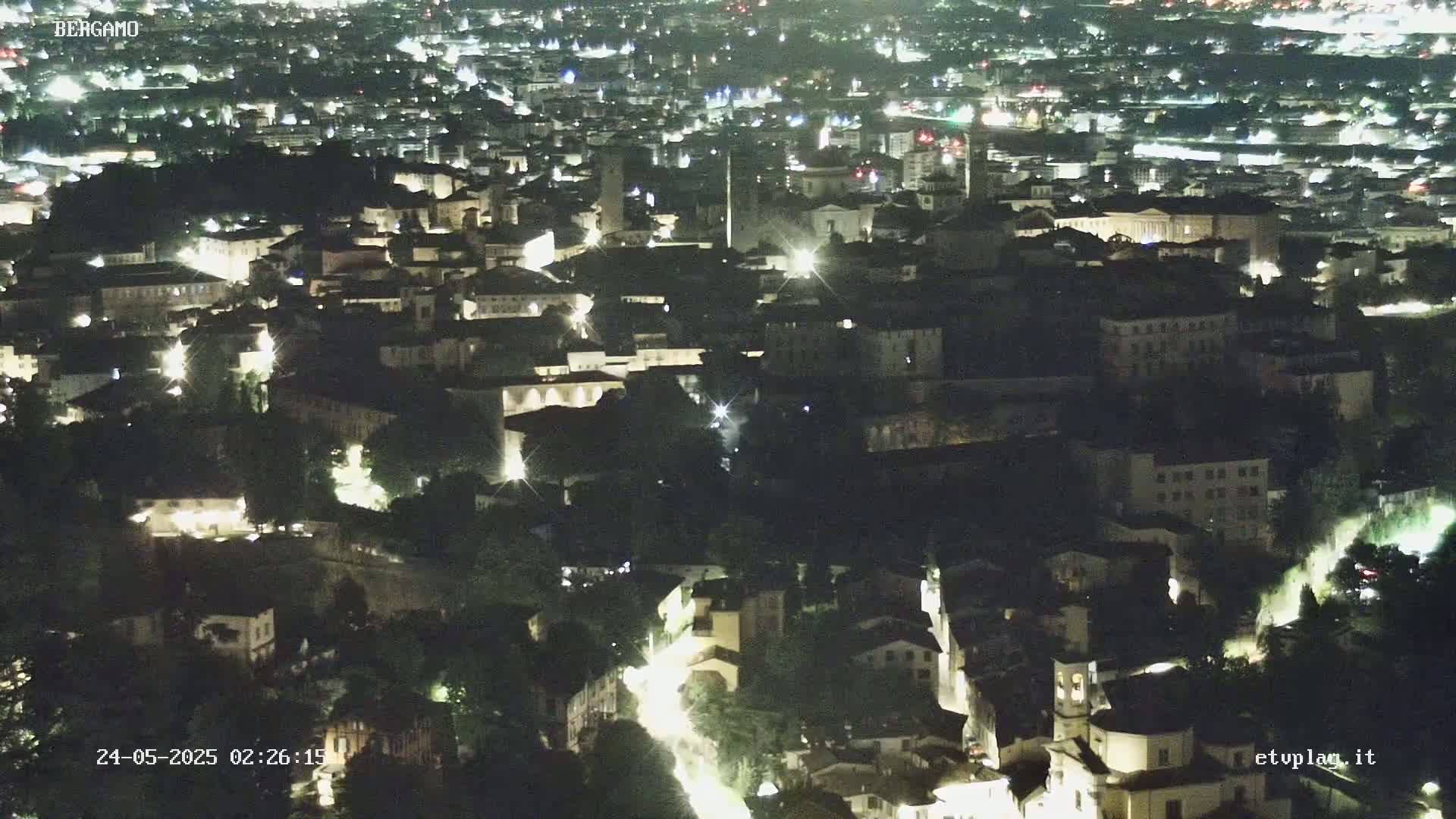 A nighttime, aerial view of a city with illuminated buildings and streets.
