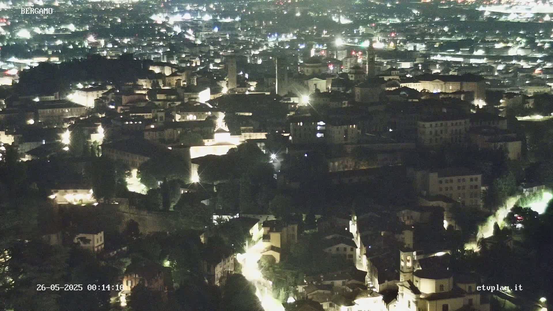 A nighttime aerial view of a city with numerous illuminated buildings and streets.