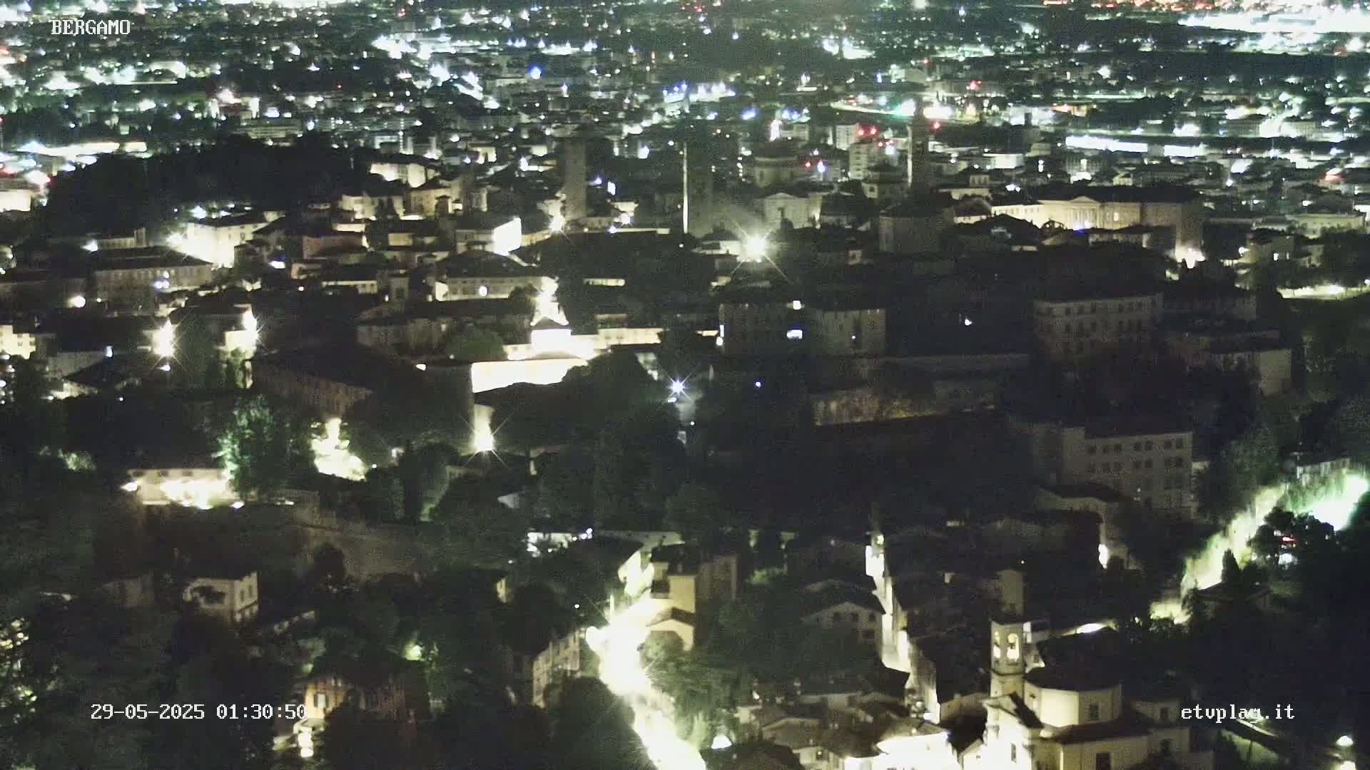A nighttime, high-angle view of a city with illuminated buildings and streets.