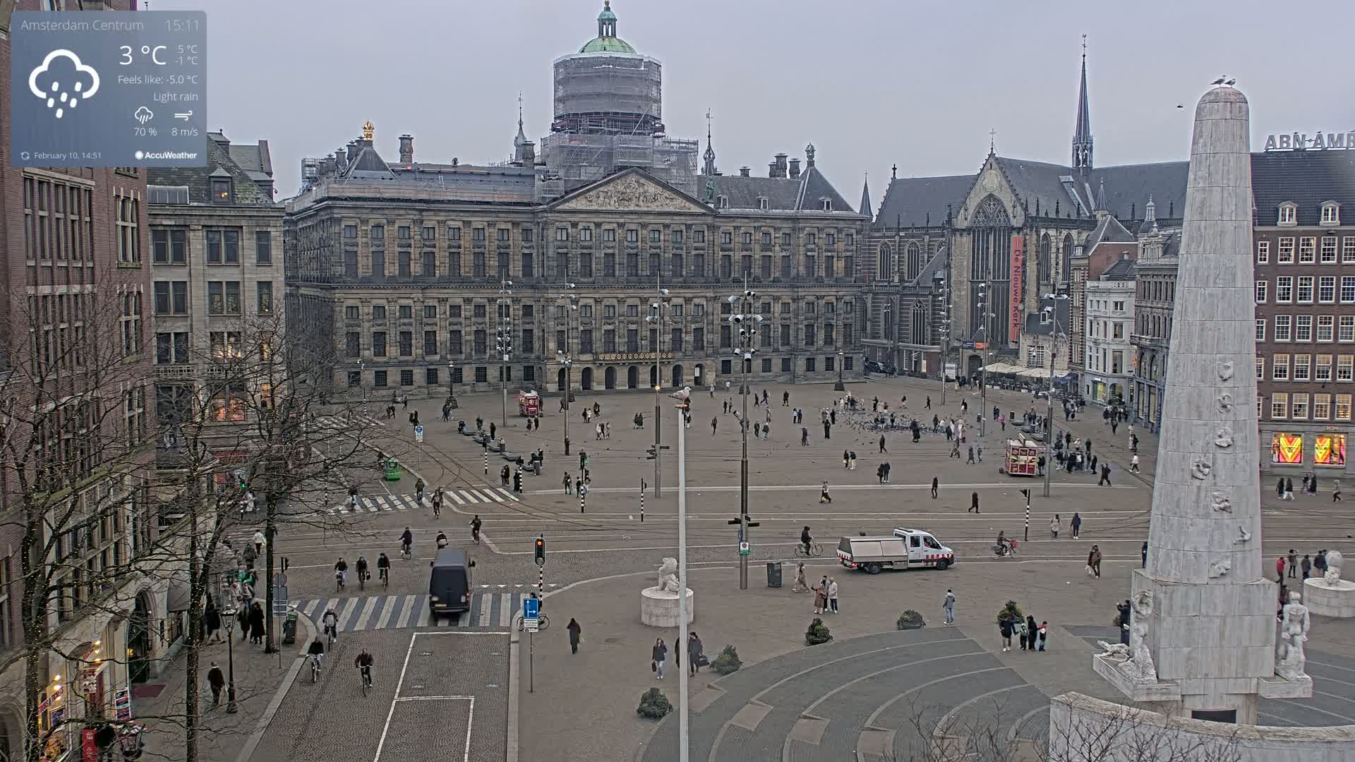 A large, grey square with a palace, church, and monument in a light rain.