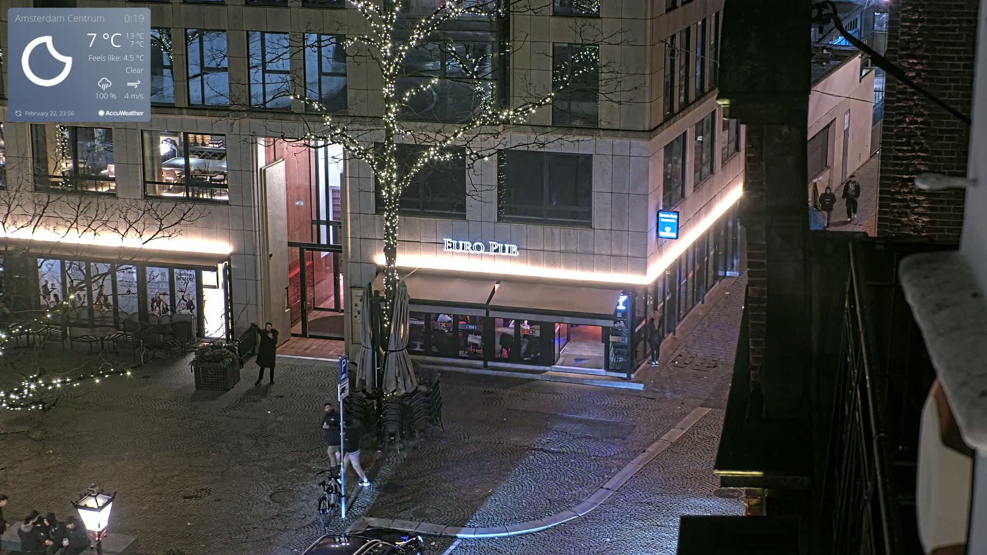 A nighttime, clear-weather view from above shows a cobblestone street with a Euro Pub and surrounding buildings, one of which is decorated with string lights on a tree.