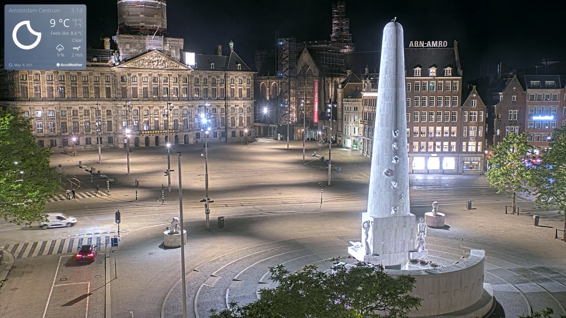A nighttime view of a large, empty square with a tall, obelisk-like monument at its center, surrounded by buildings under a clear sky.