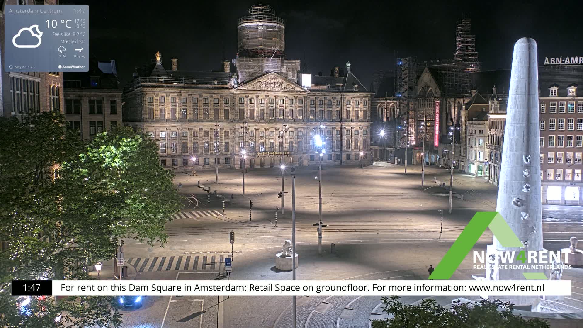A mostly clear night scene shows a large, empty square with a palace and other buildings illuminated, under a 10°C temperature.