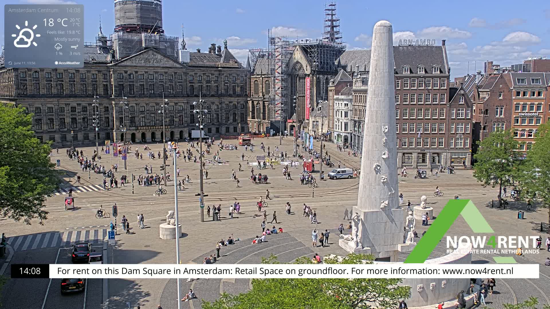 A mostly sunny Dam Square in Amsterdam shows a large crowd of people around a monument, with buildings and tram tracks surrounding the square.