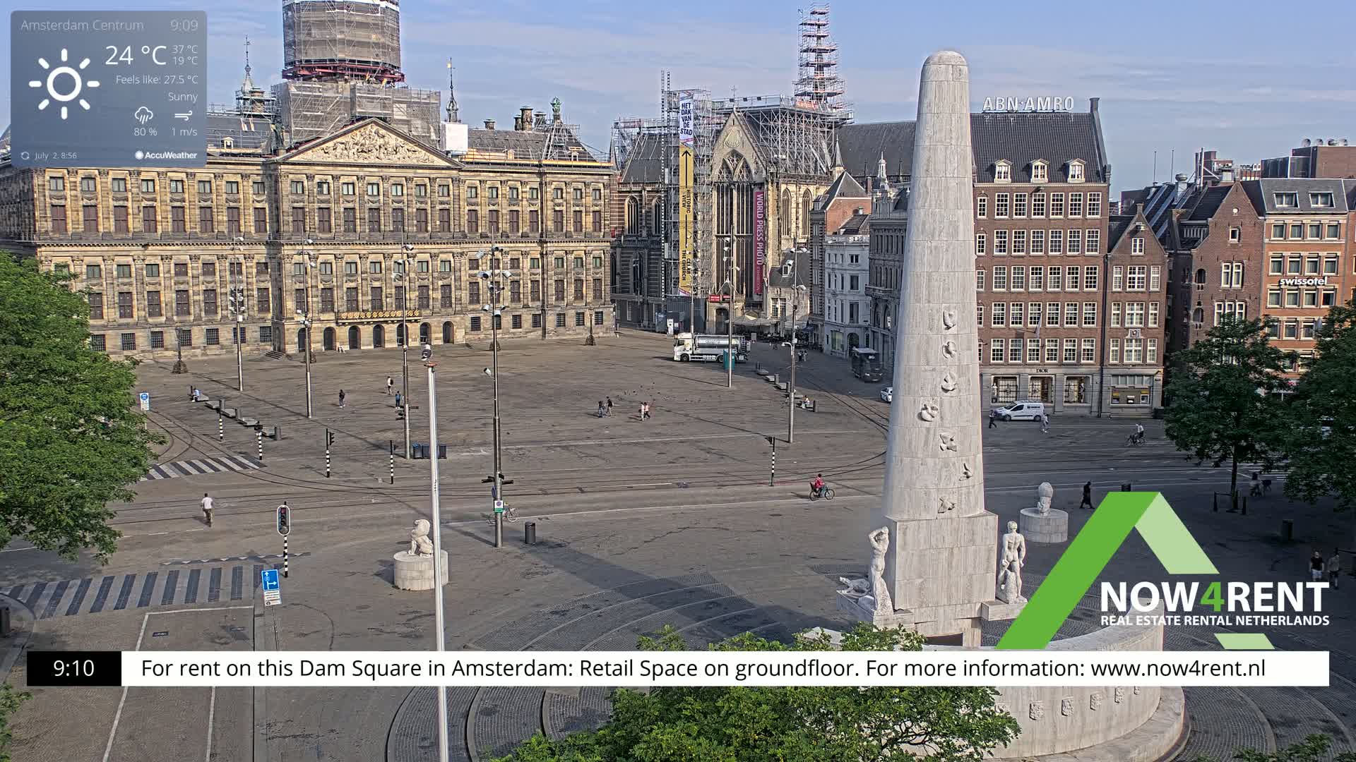 A sunny Dam Square in Amsterdam shows a large plaza with a monument at its center, surrounded by buildings, some under construction.