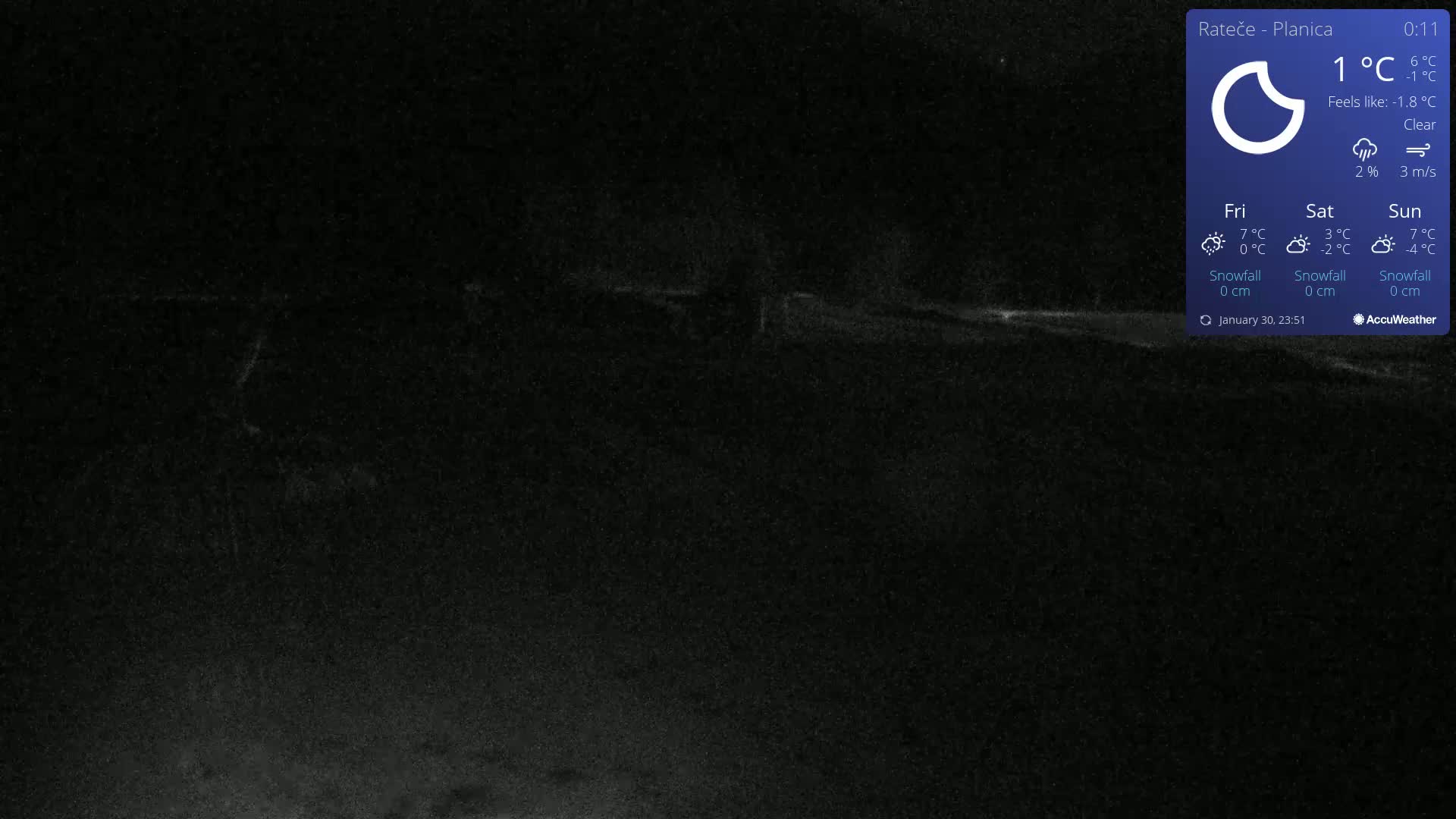A dark, nighttime scene under a clear sky shows a dimly lit, snow-covered ground.