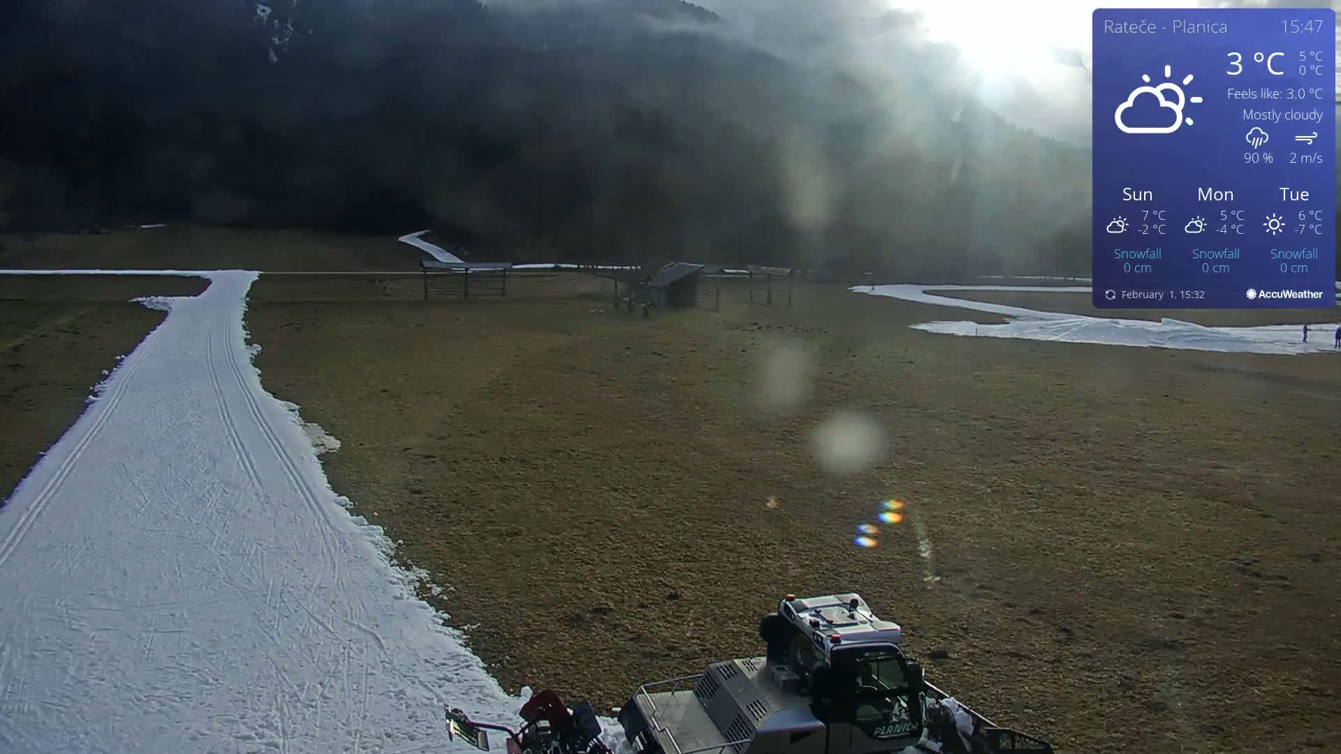 A snow groomer is parked near a snow-covered cross-country ski trail in a mostly cloudy, 3°C outdoor setting with brown grass surrounding the trail.