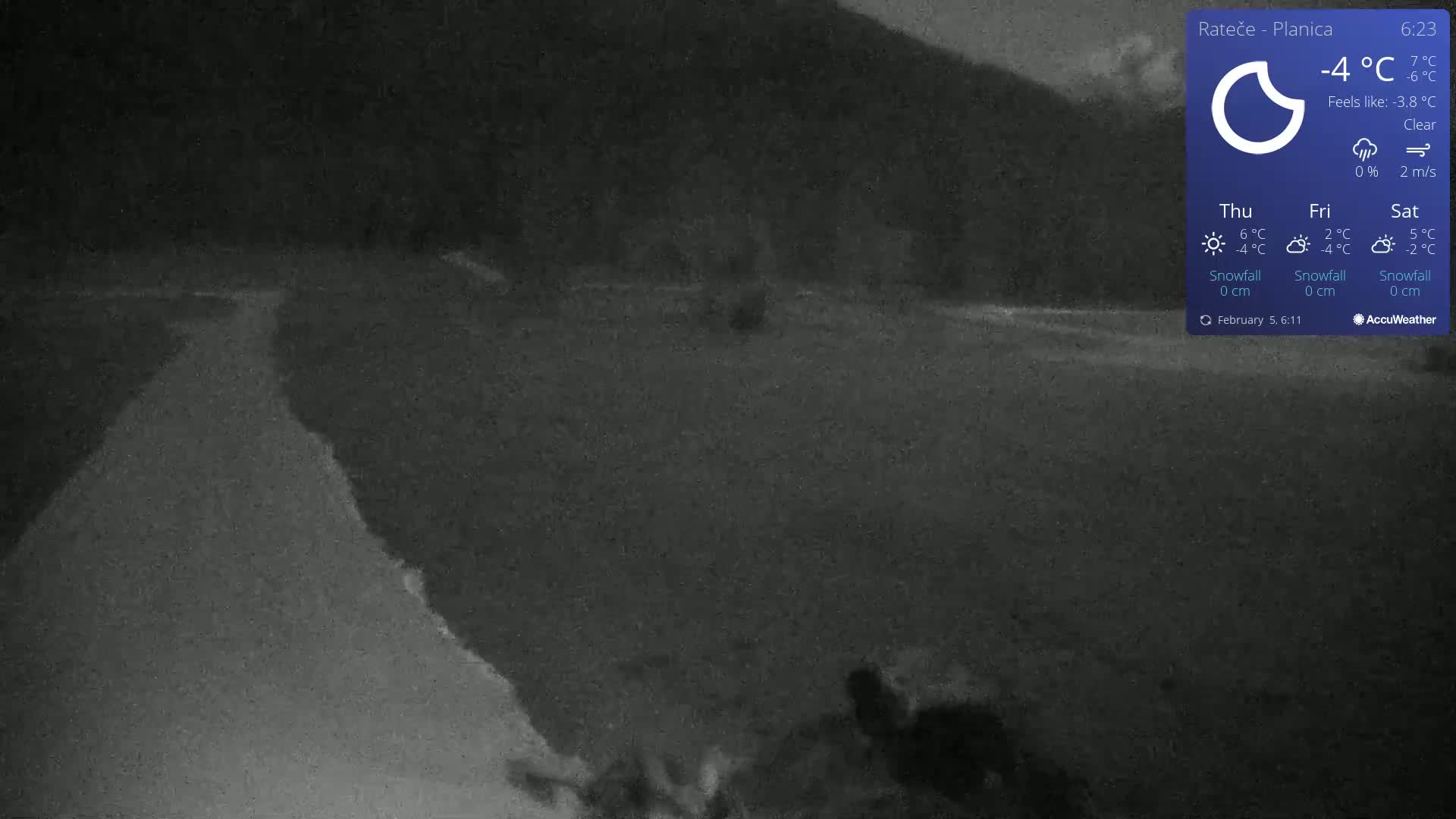 A dark, nighttime scene shows a snow-covered road leading toward a mountain under a clear sky.