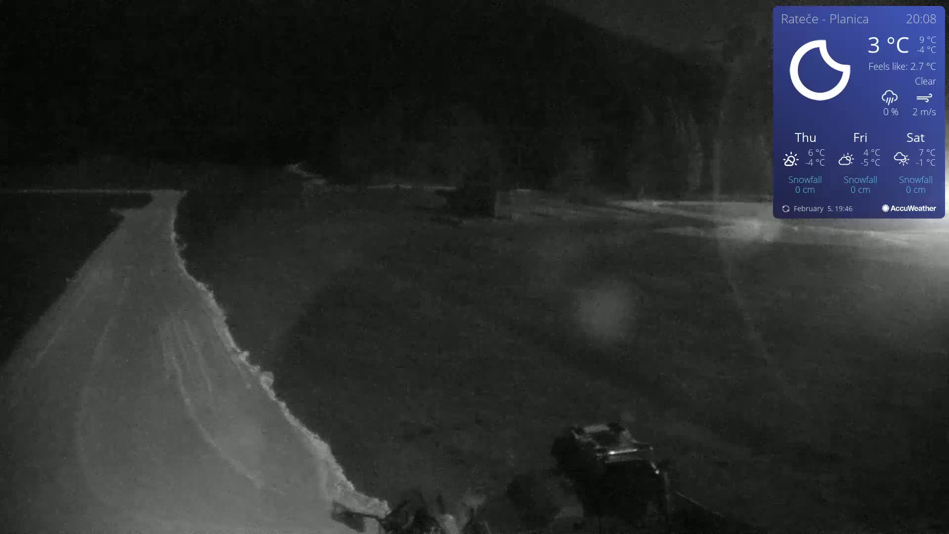 A dark, snow-covered road curves gently under a clear night sky.
