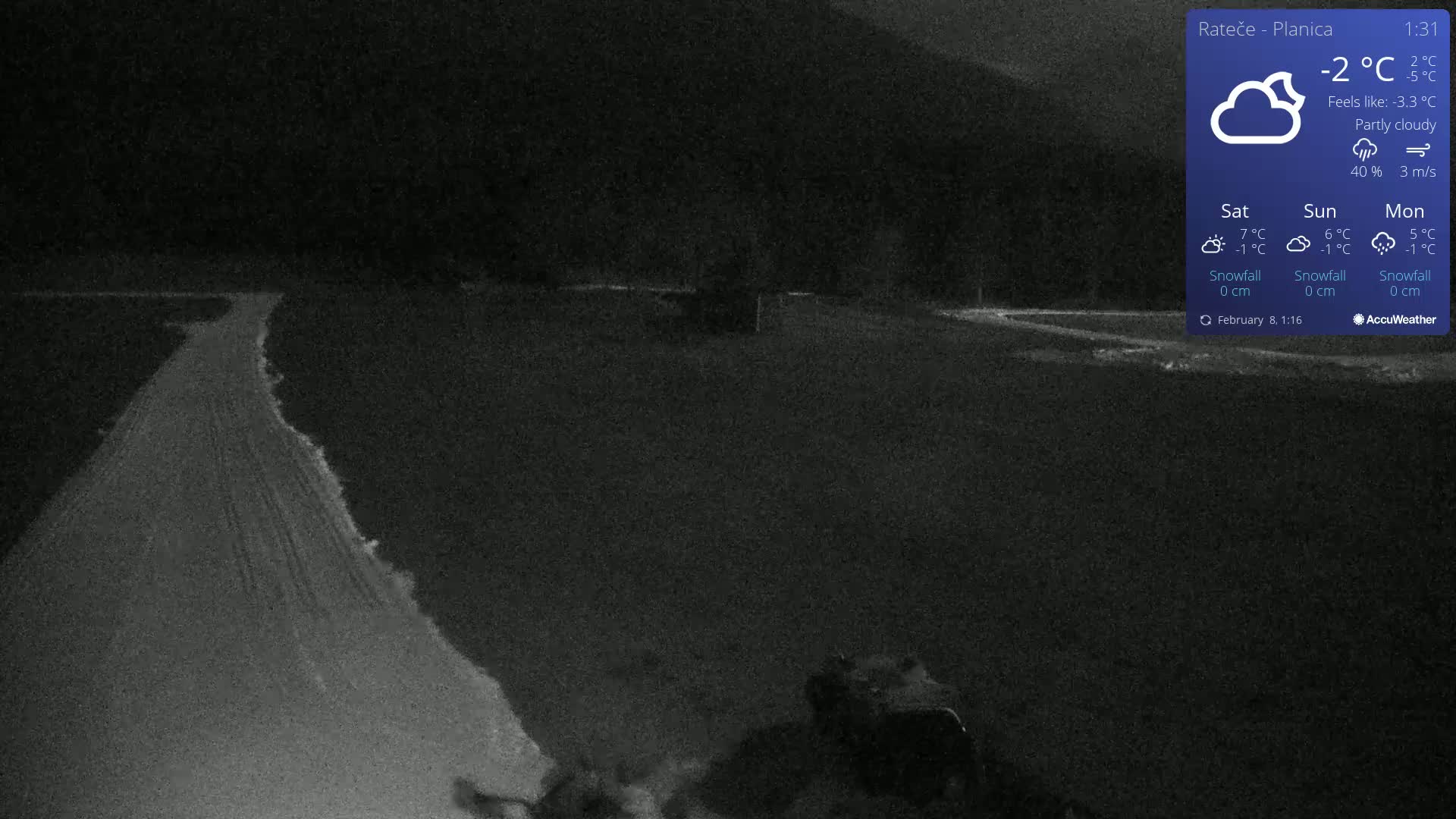 A snow-covered road winds through a dark, partly cloudy night landscape.