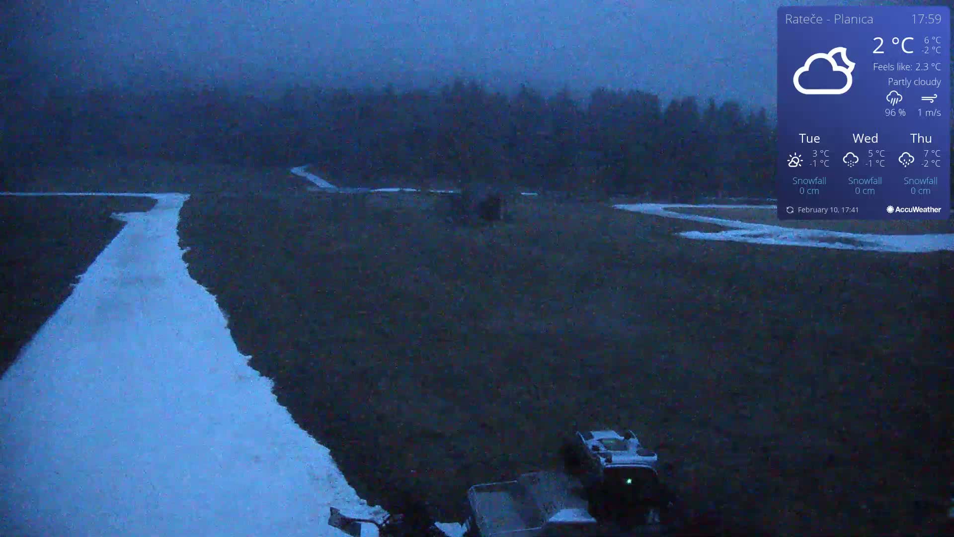 A snow-covered path winds through a dark, partly cloudy landscape under a twilight sky.