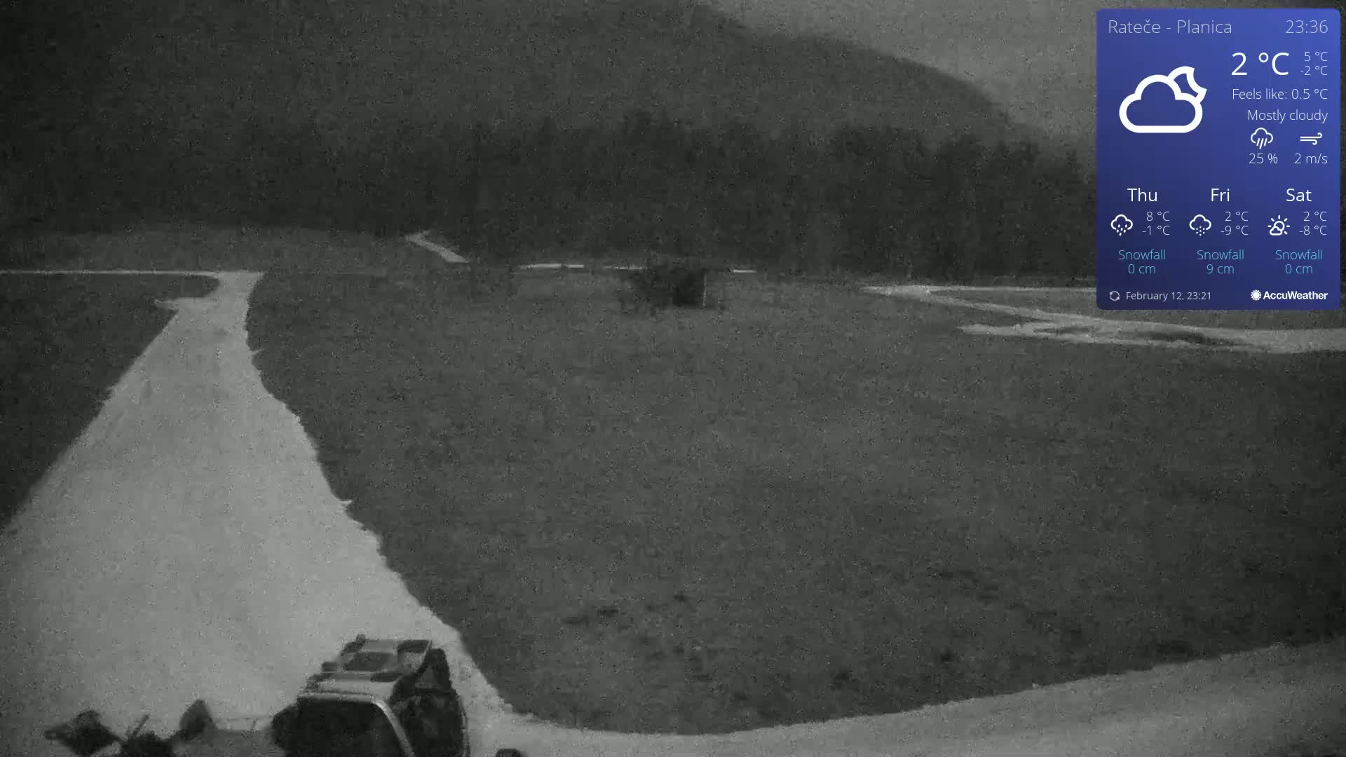 A mostly cloudy night scene shows a flat, dark-colored expanse of land with a light-colored path curving through it, a vehicle at the bottom, and dark hills in the background.