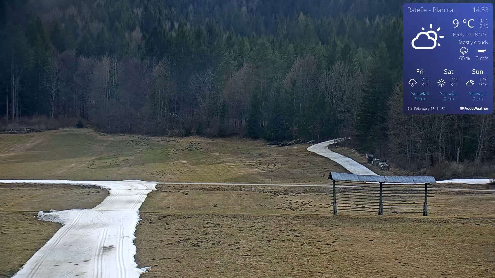 A mostly cloudy, 9°C day shows a snow-covered path winding through a grassy field toward a wooded area, with a wooden structure visible in the foreground.
